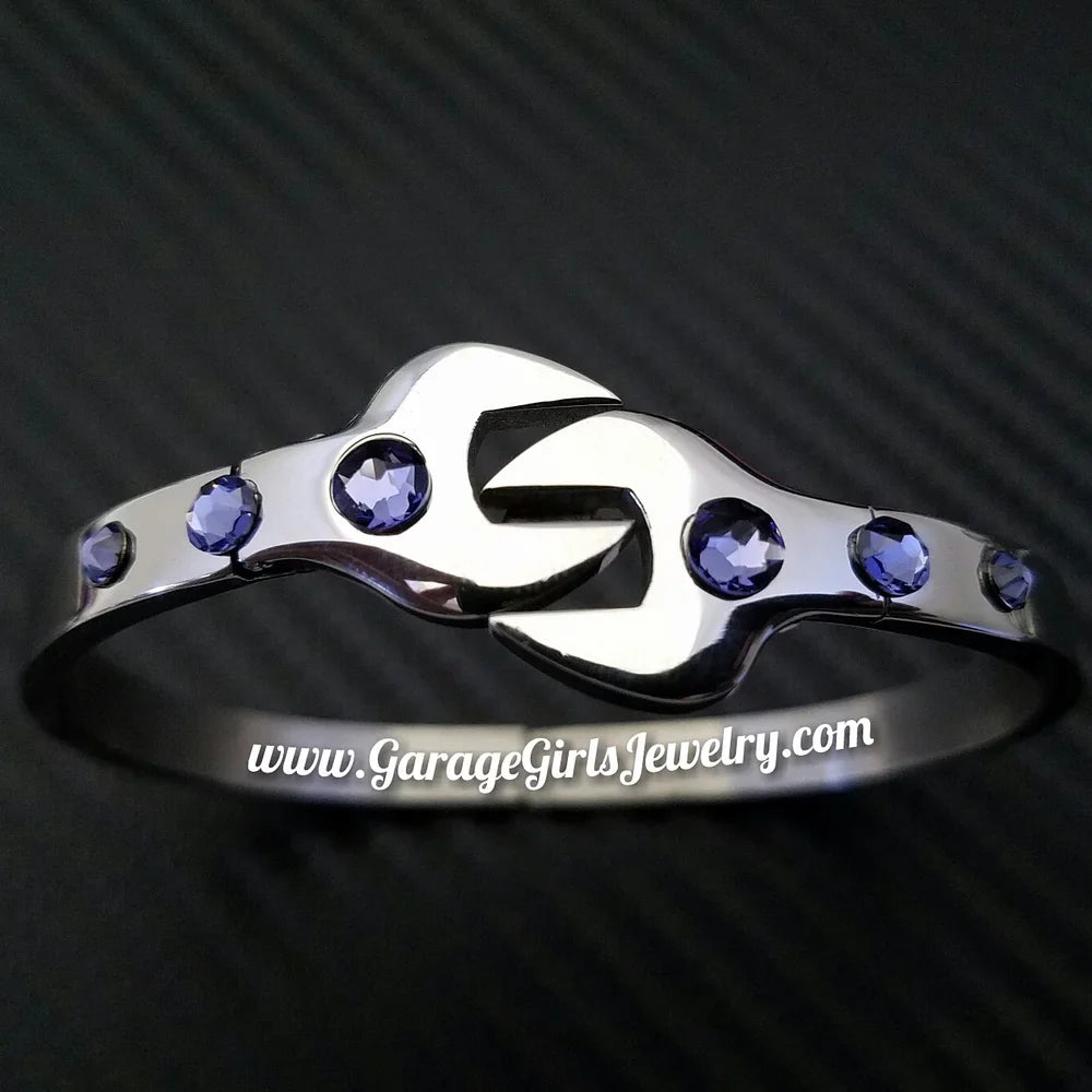Silver wrench bracelet with purple gemstones on a black textured background, featuring the brand 'Garage Girls Jewelry'.