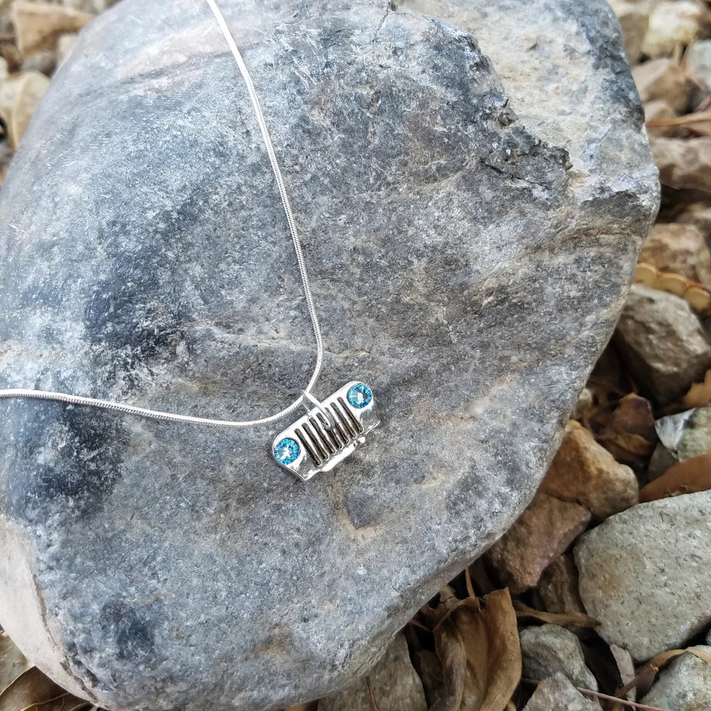 Necklace with a small Jeep Grille pendant on a rock