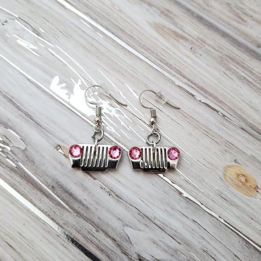 Silver earrings with pink gemstones on a marble surface
