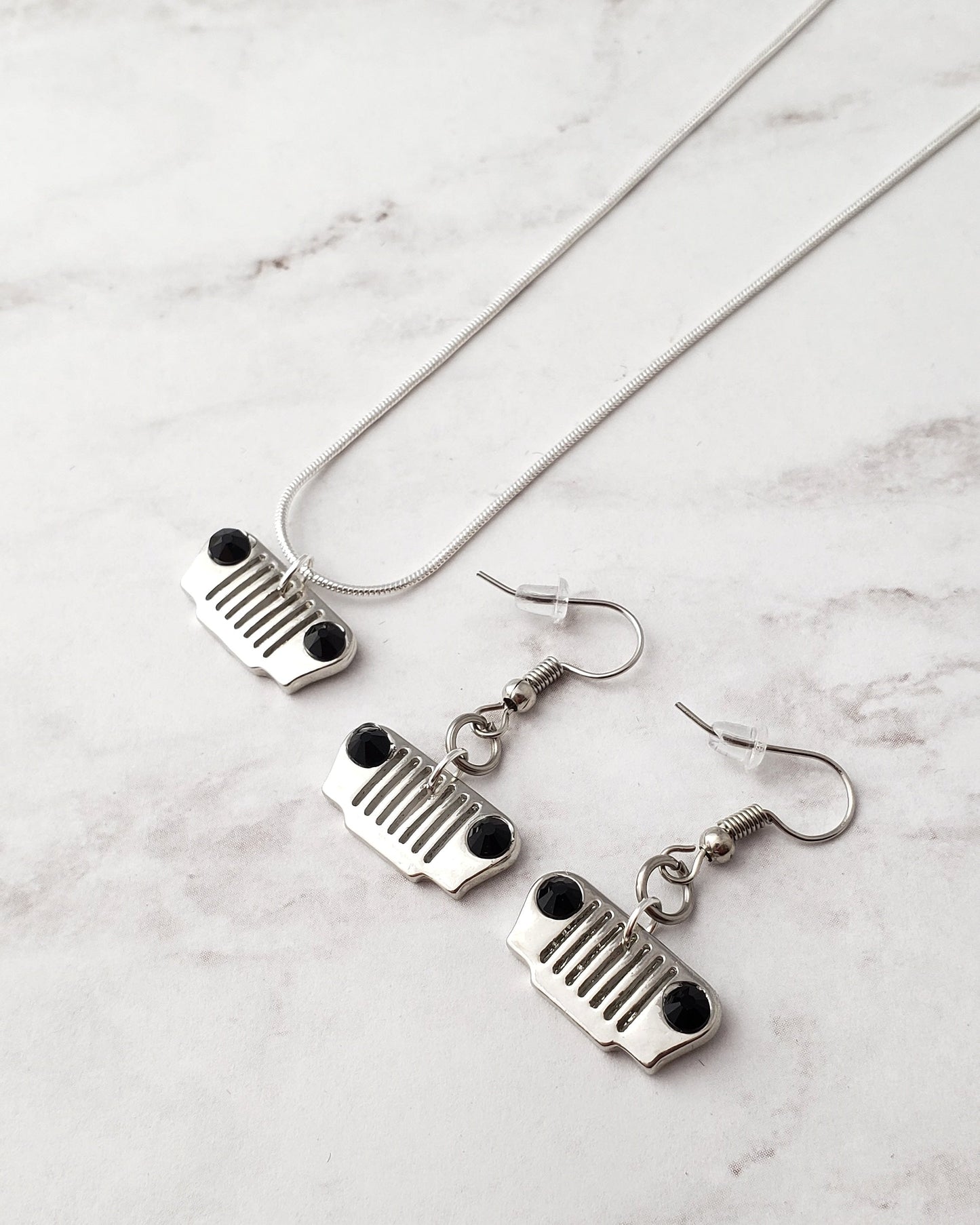 Jewelry set with necklace and earrings featuring grille designs on a marble surface