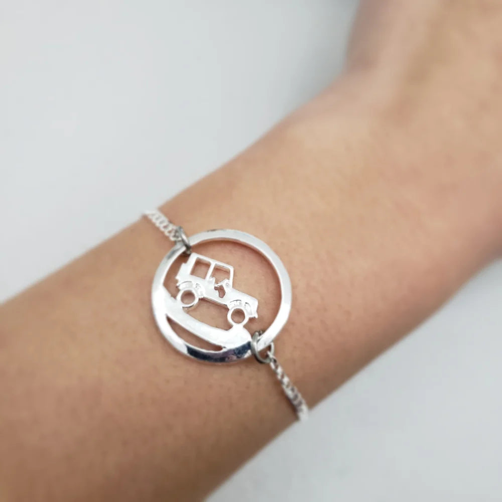 Silver bracelet with a Jeep design on a wrist against a light background