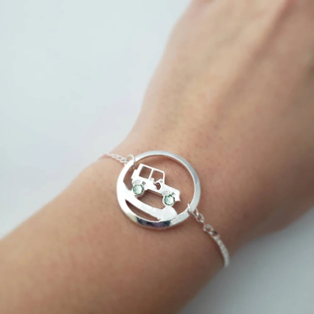 Silver bracelet with a car design on a wrist against a white background