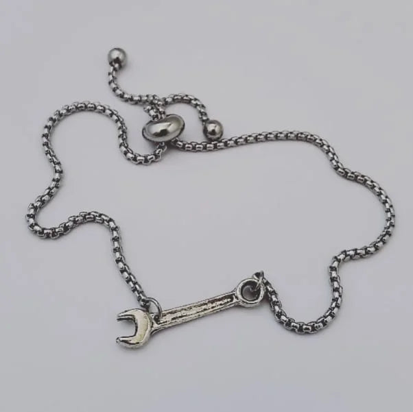 Silver chain necklace with a wrench pendant on a light gray background