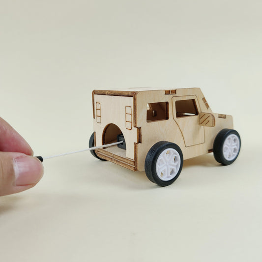 Small wooden model of a vehicle on wheels with a hand holding a string.