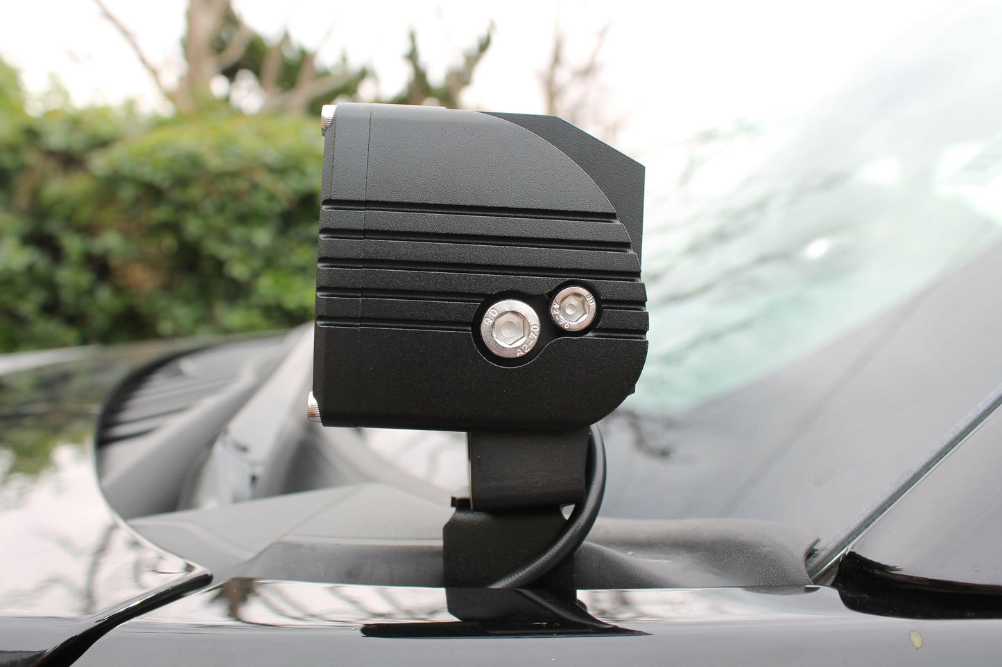 Black car light mounted on a car roof with a blurred outdoor background
