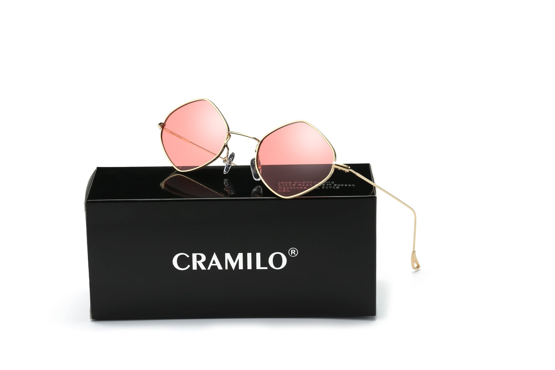 Pink sunglasses with gold frames on a black Cramilo branded case.