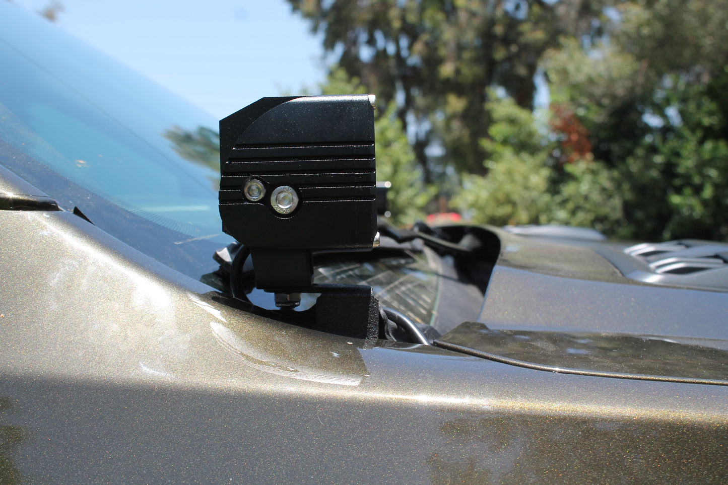 LED light fixture on a car hood with trees in the background
