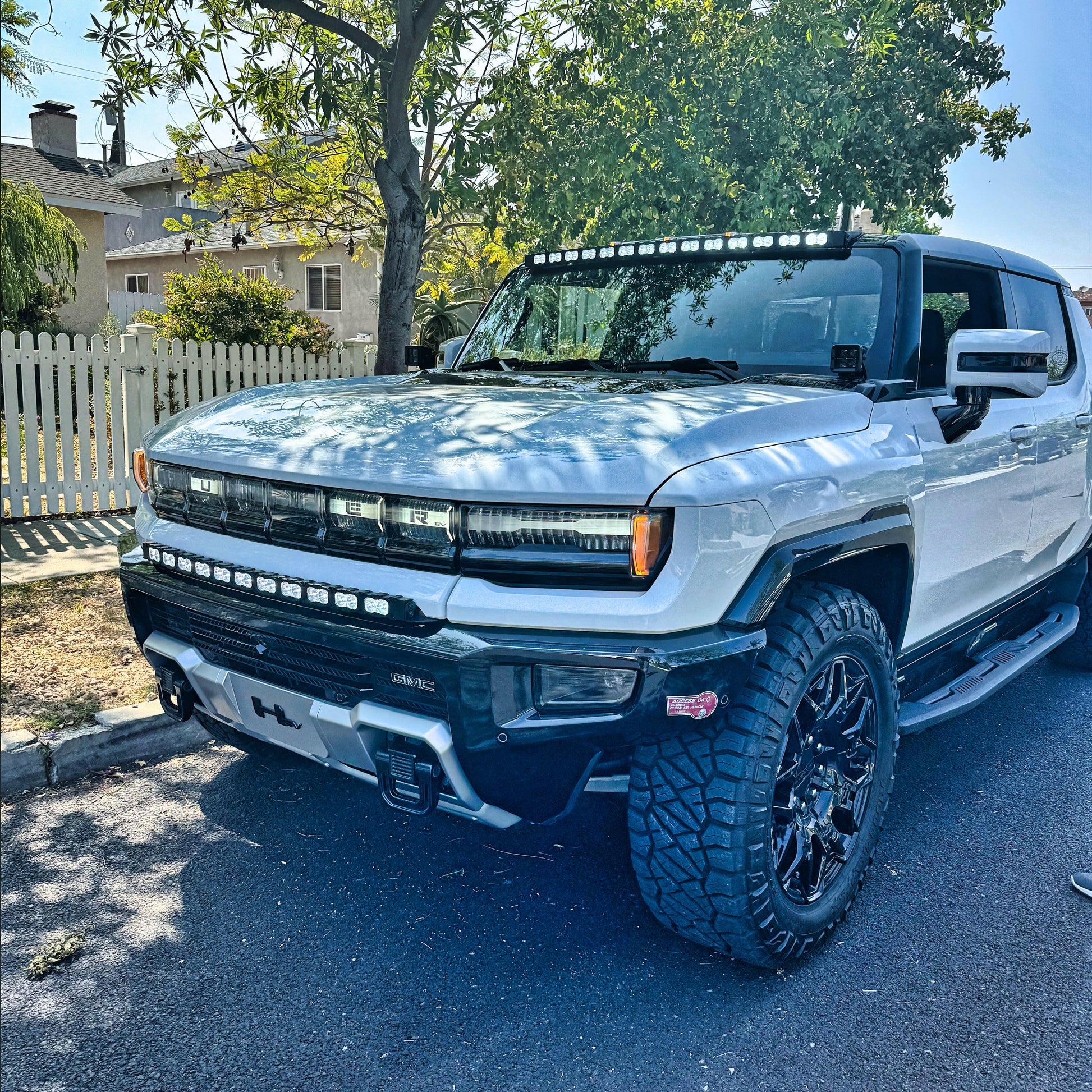 White pickup truck with large off-road tires parked on a residential street.