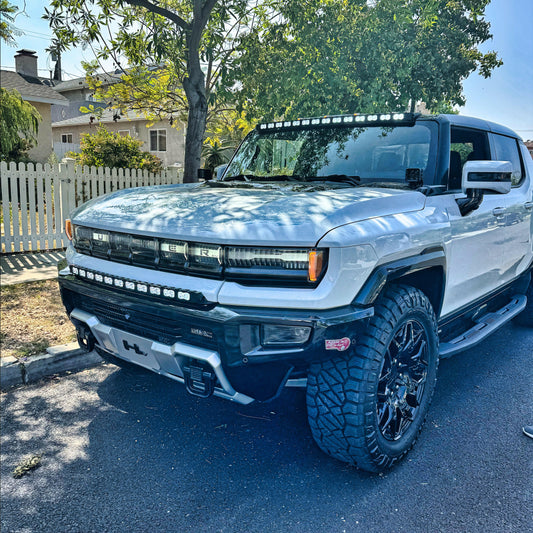 White pickup truck with large off-road tires parked on a residential street.