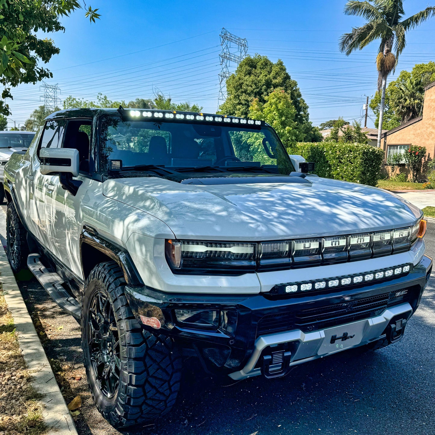 White hummer truck with additional lights on a residential street
