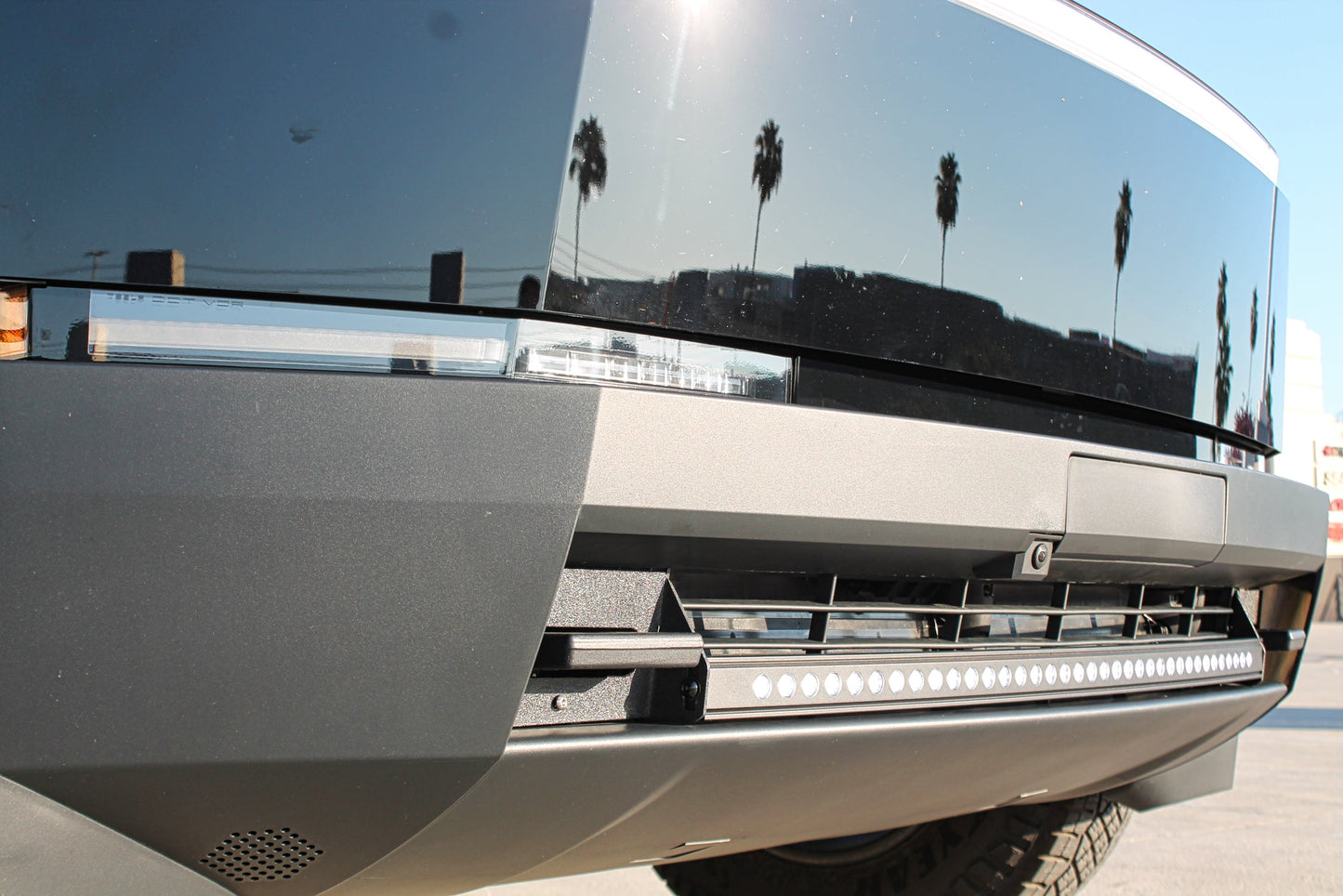 Close-up of a modern vehicle's front bumper with reflective surface ald LED light strip