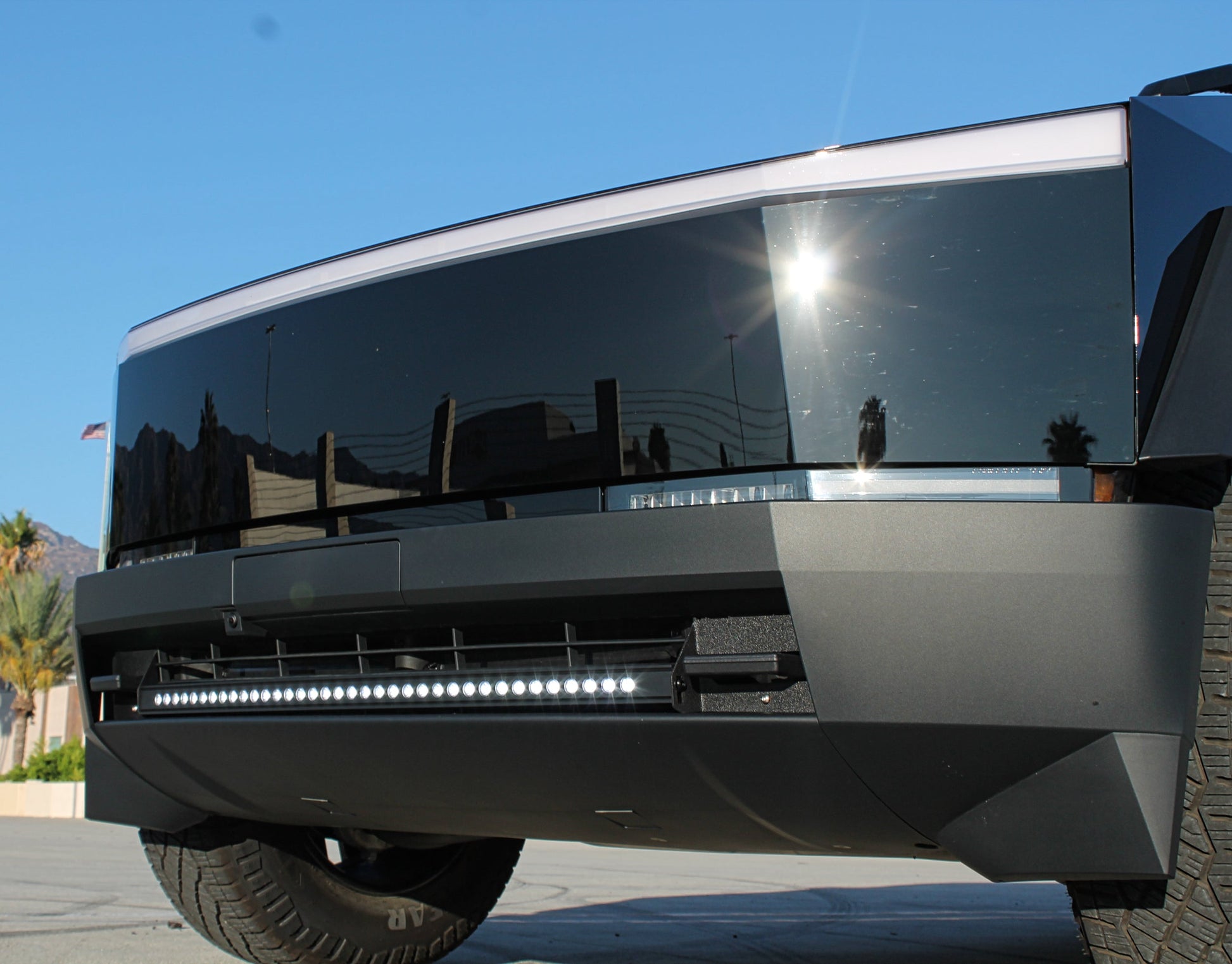 Front view of a tesla vehicle with reflective surface and clear sky background