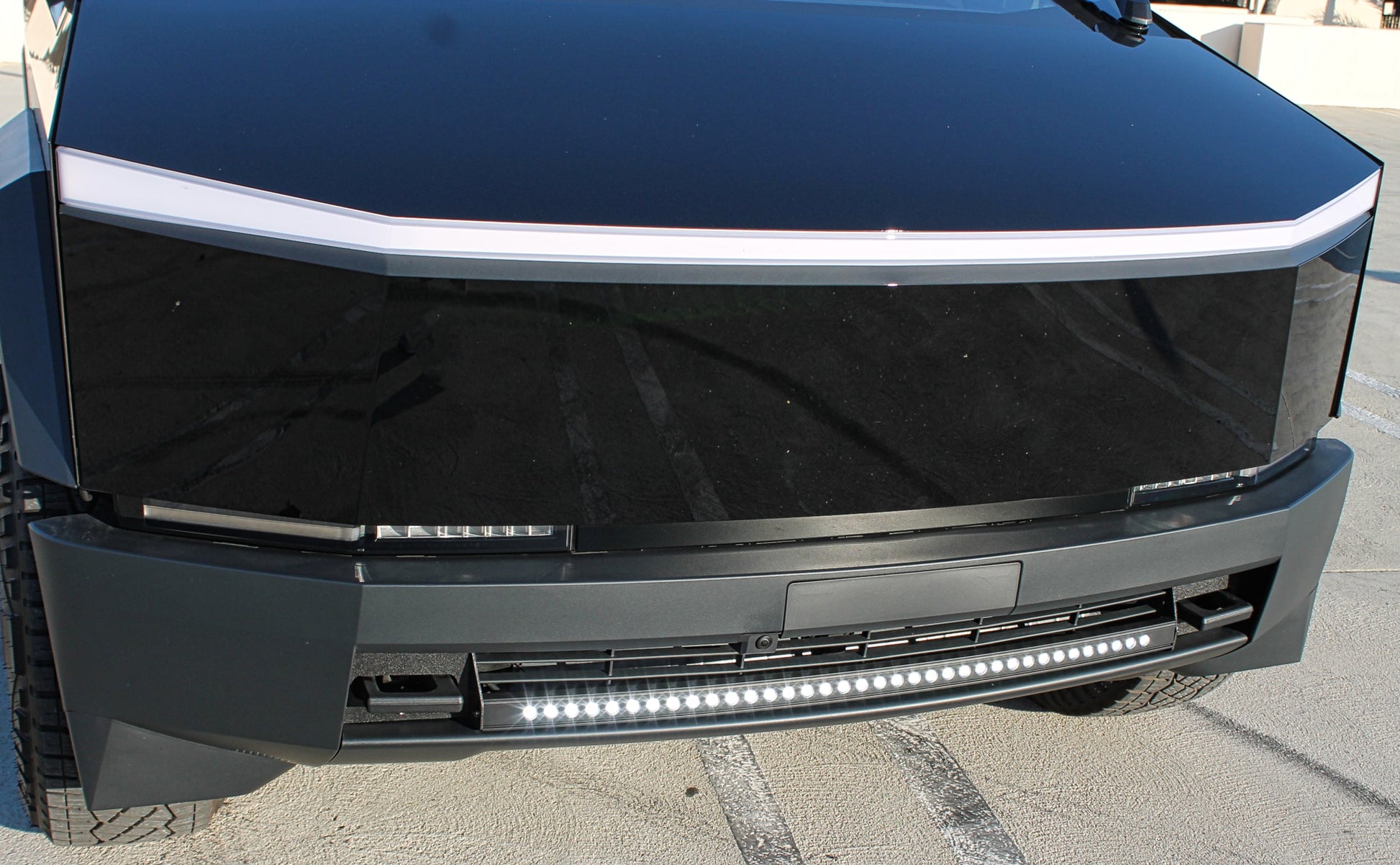 Close-up of a vehicle's front bumper with LED lights on a pavement background