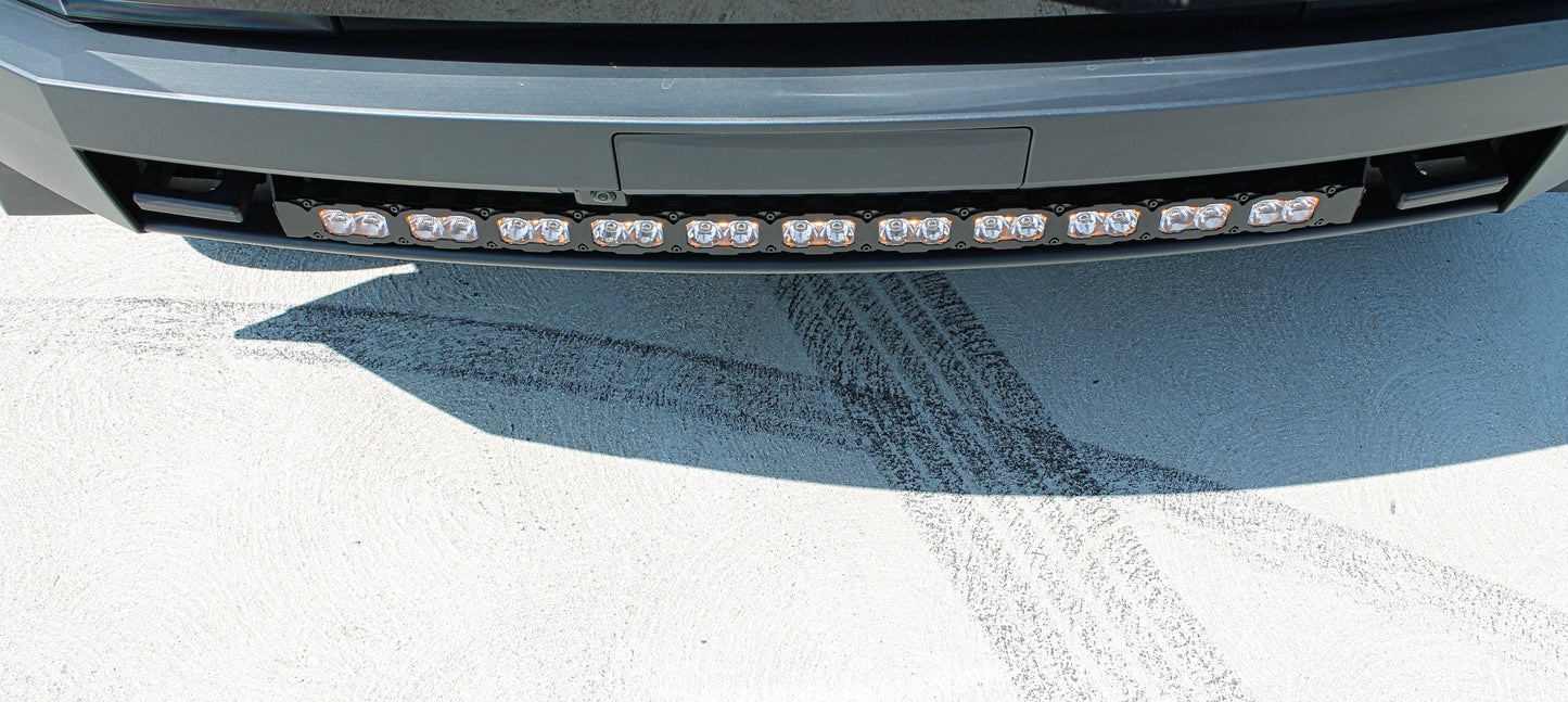 Close-up of a vehicle's front bumper with LED lights on a snowy road.