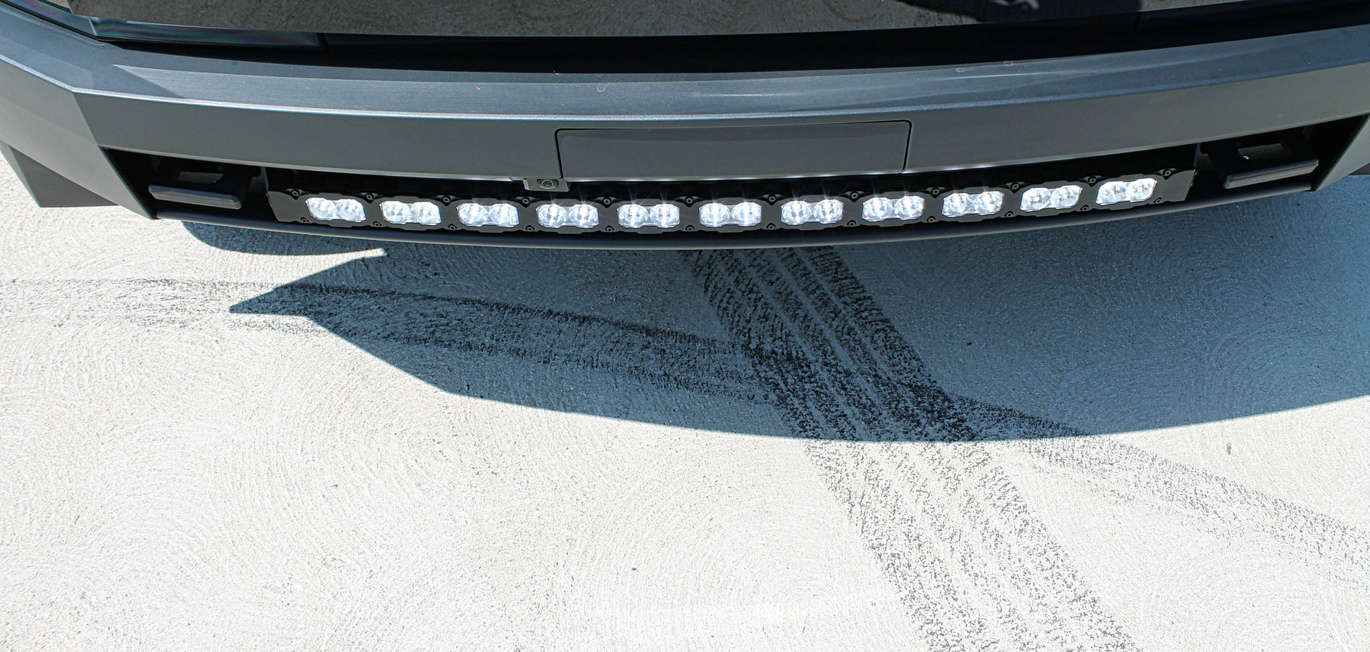 Close-up of a tesla's front bumper with LED lights on a snowy road.