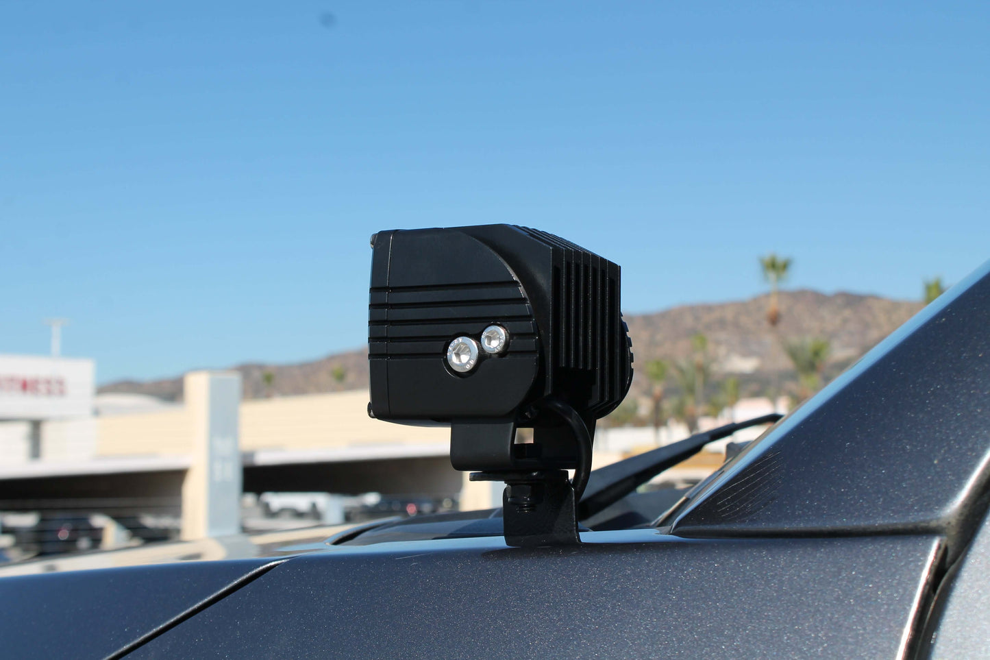Black LED work light on a car roof with a clear blue sky background