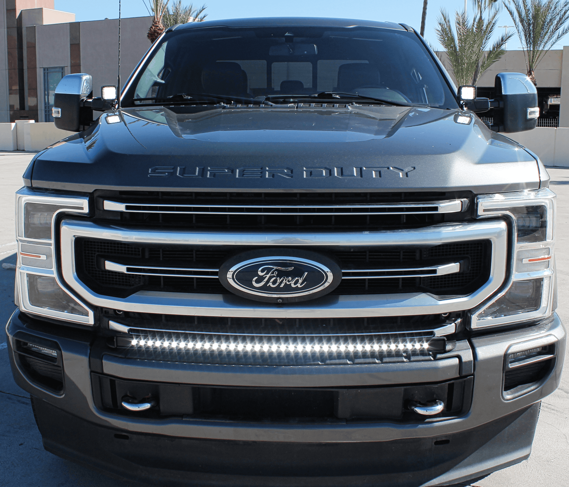 Front view of a Ford Super Duty truck with clear sky and buildings in the background