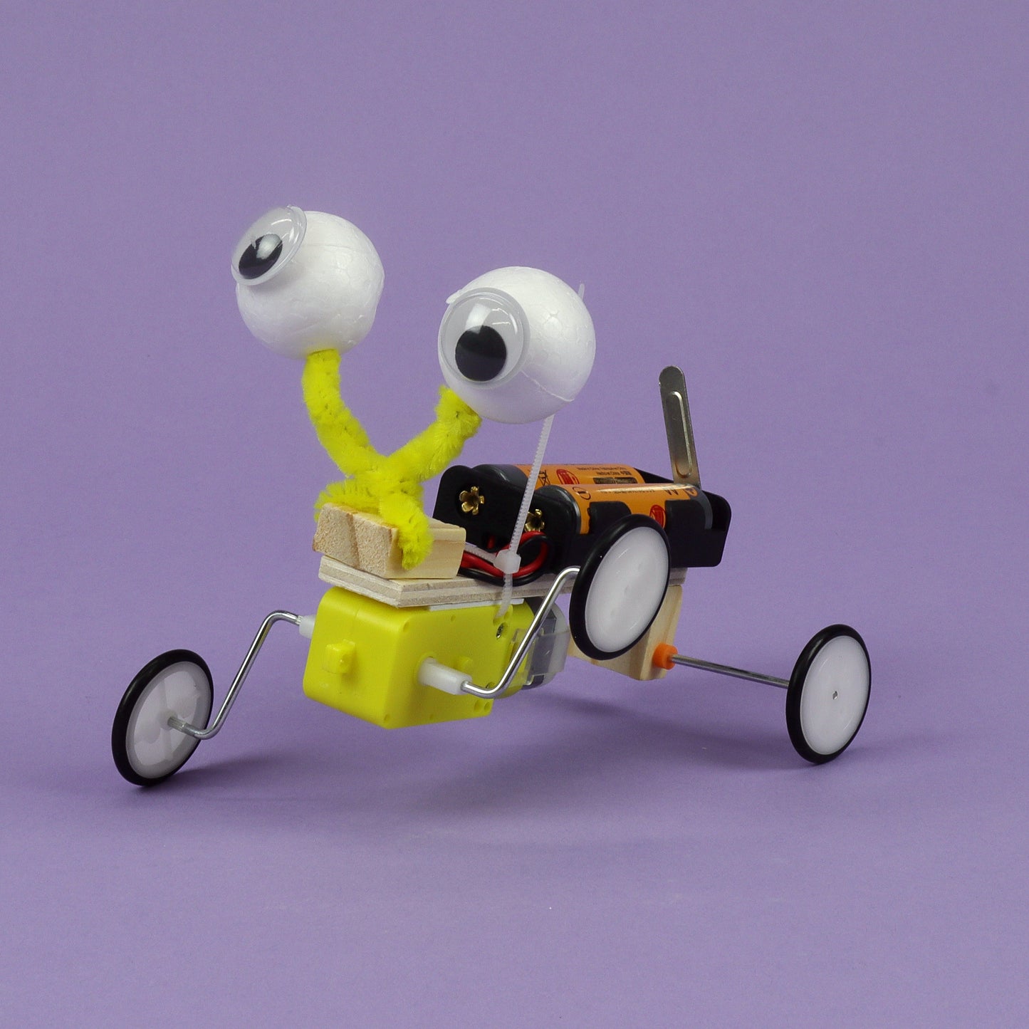 Toy figure with googly eyes and a small vehicle on a purple background