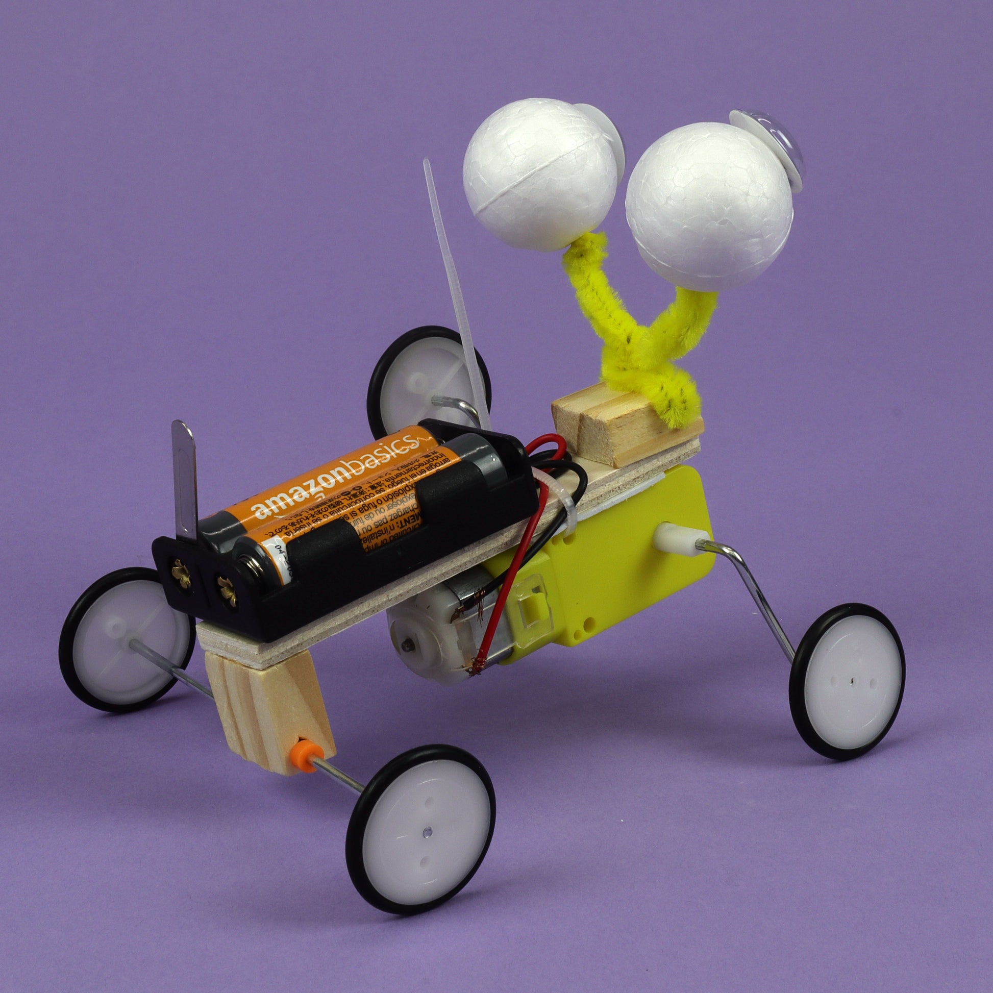 Toy car with tennis ball eyes on a purple background