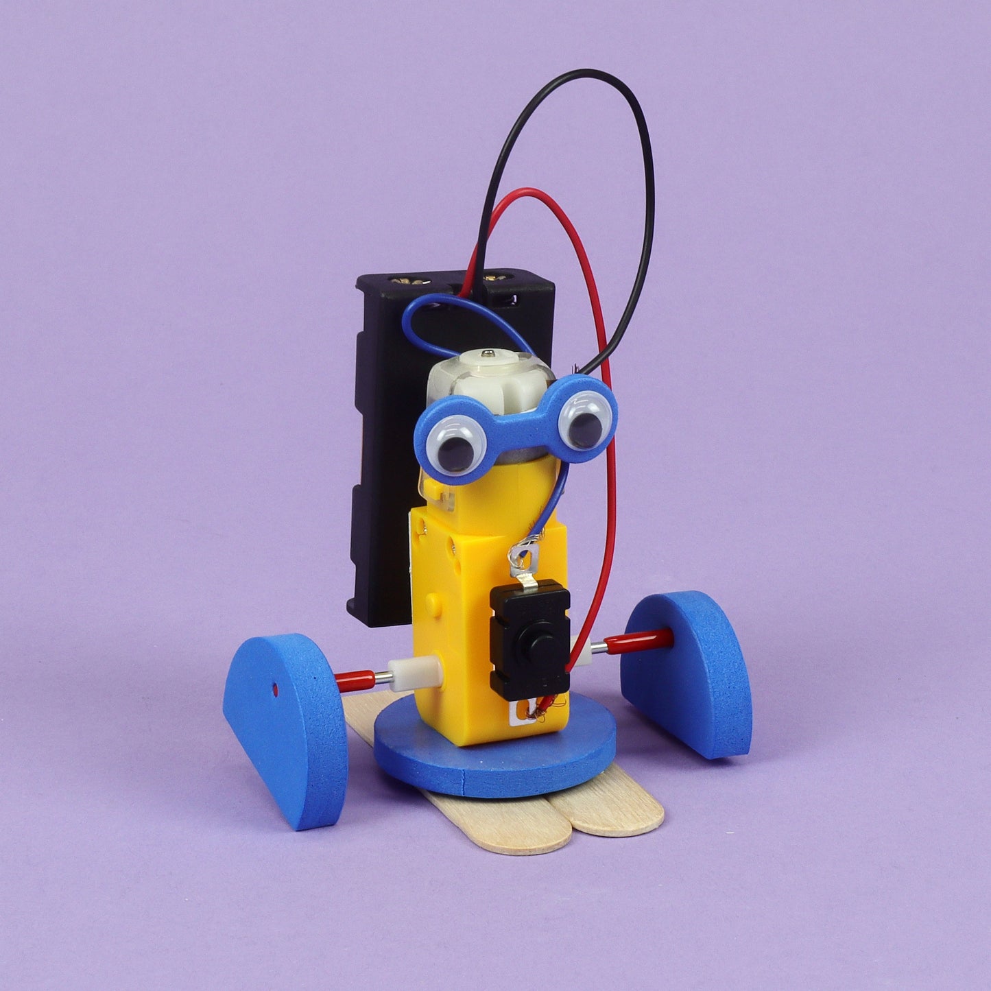 Toy robot with googly eyes and blue wheels on a purple background