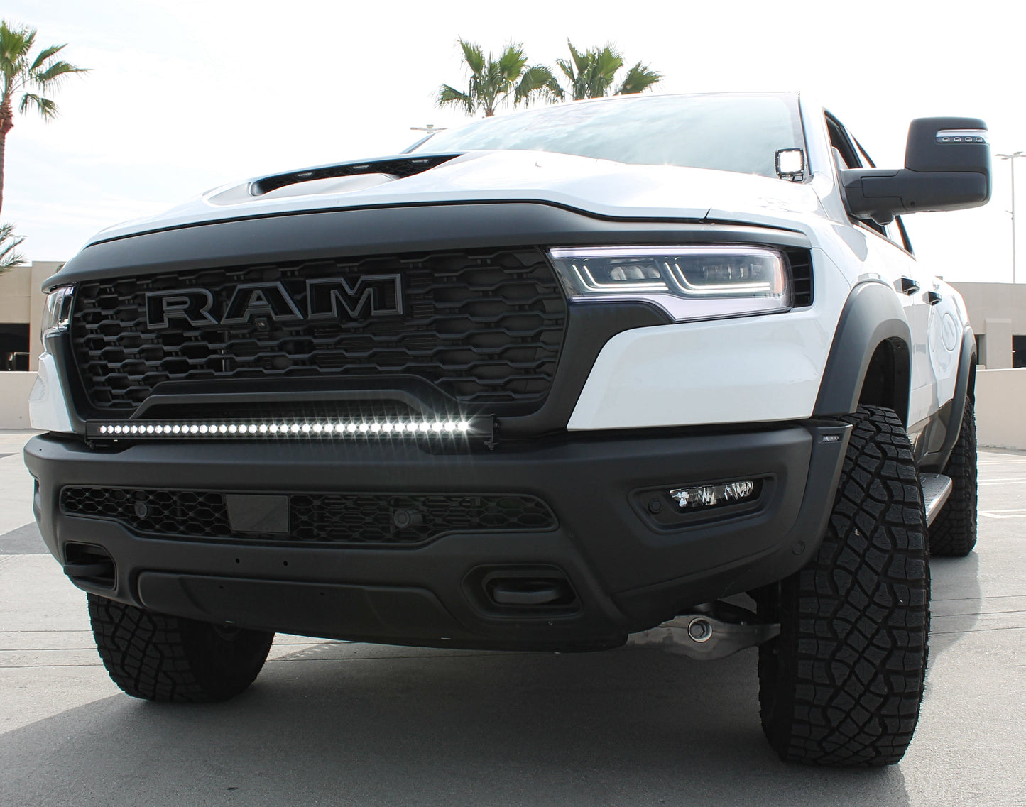 White Ram truck with black grille and LED light bar on a concrete surface.
