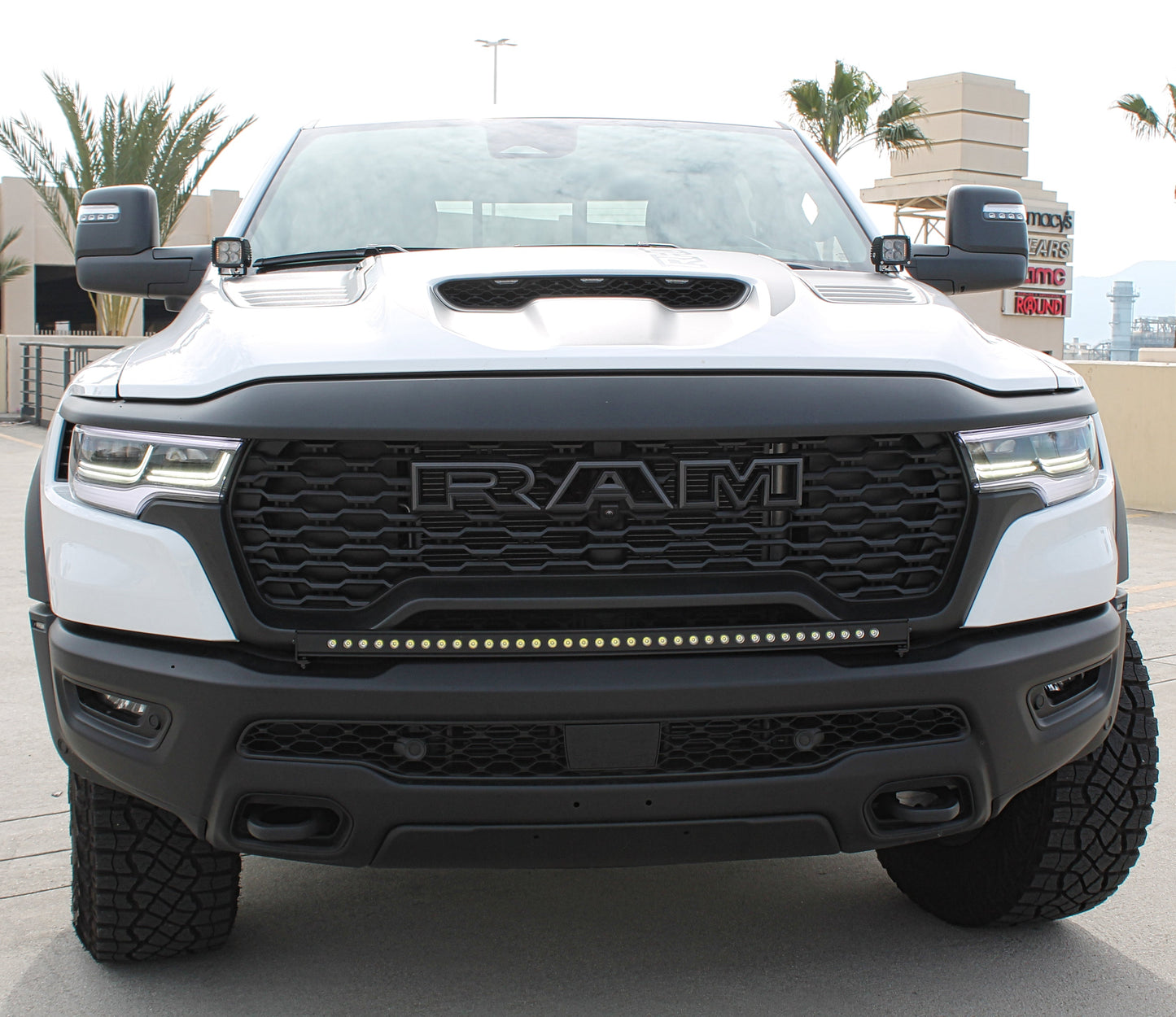 White Ram truck with black grille and LED light bar on a concrete surface.