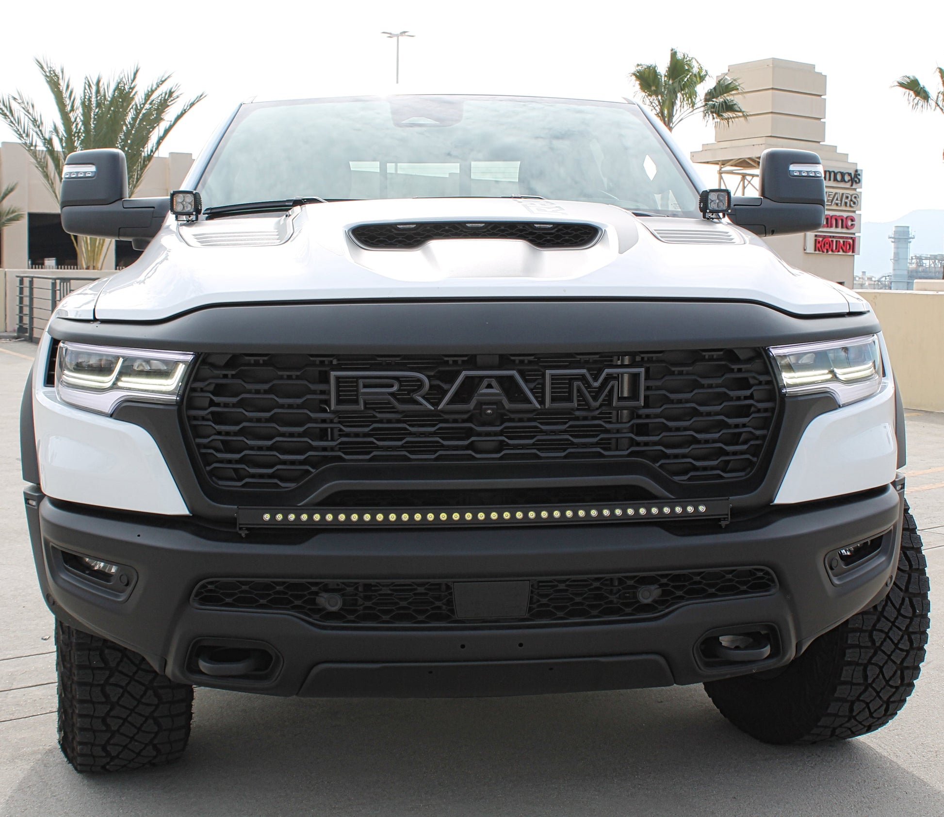 White Ram truck with black grille and LED light bar on a concrete surface.