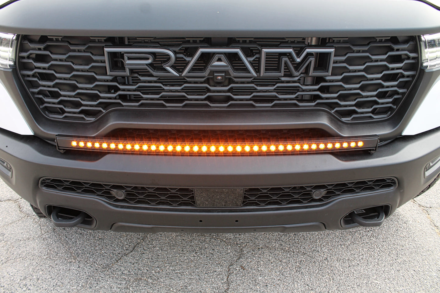 Close-up of a Ram truck grille with LED light bar on a concrete surface