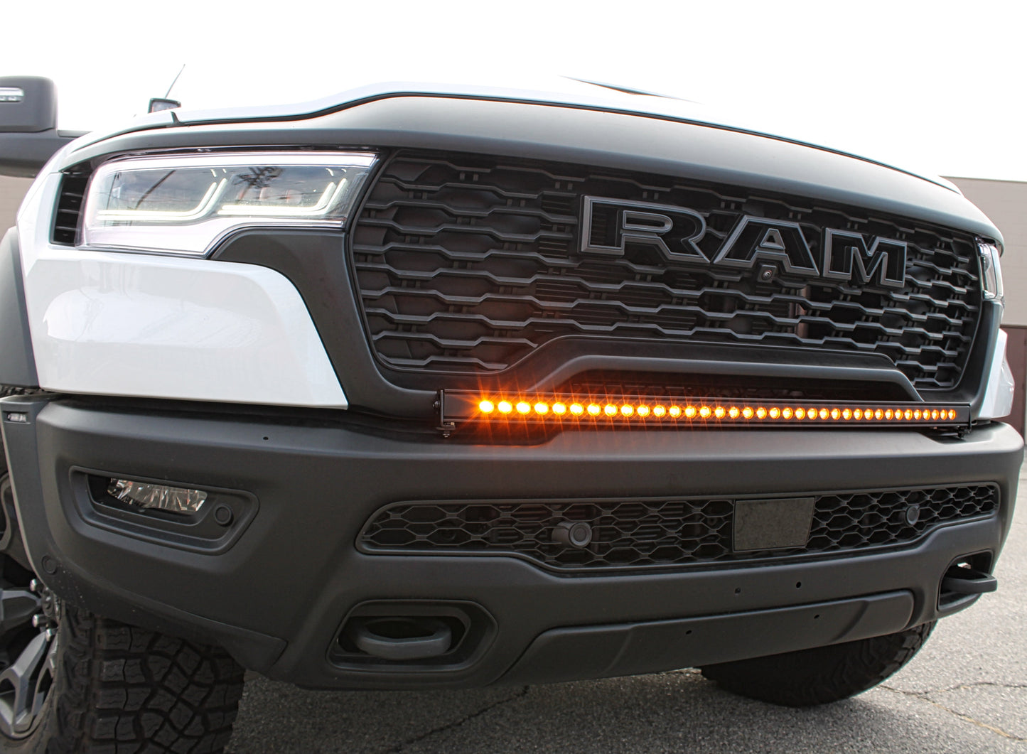 Close-up of a Ram truck's front grille with visible branding and amber Light Bar.