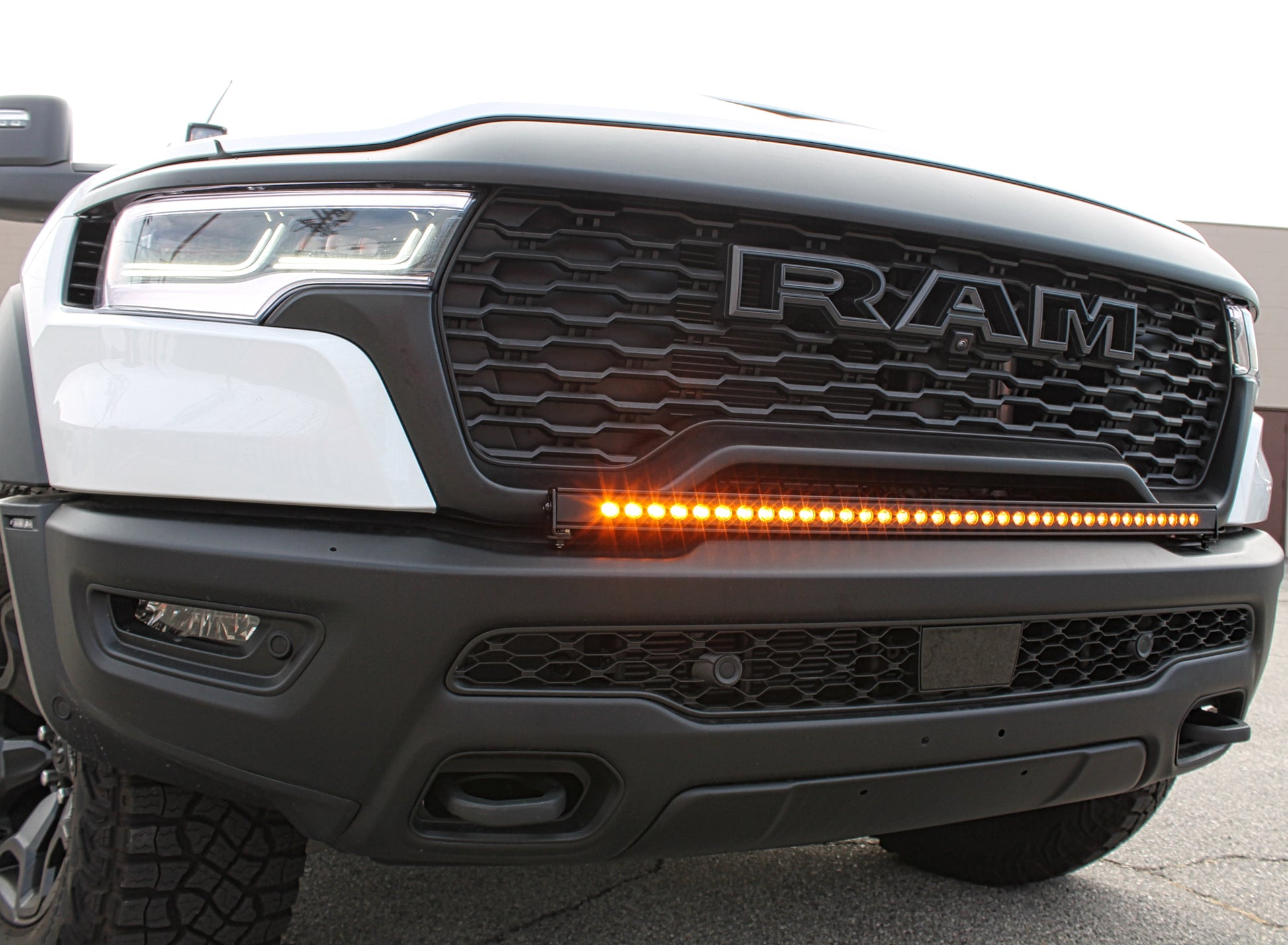 Close-up of a Ram truck's front grille with visible branding and amber Light Bar.