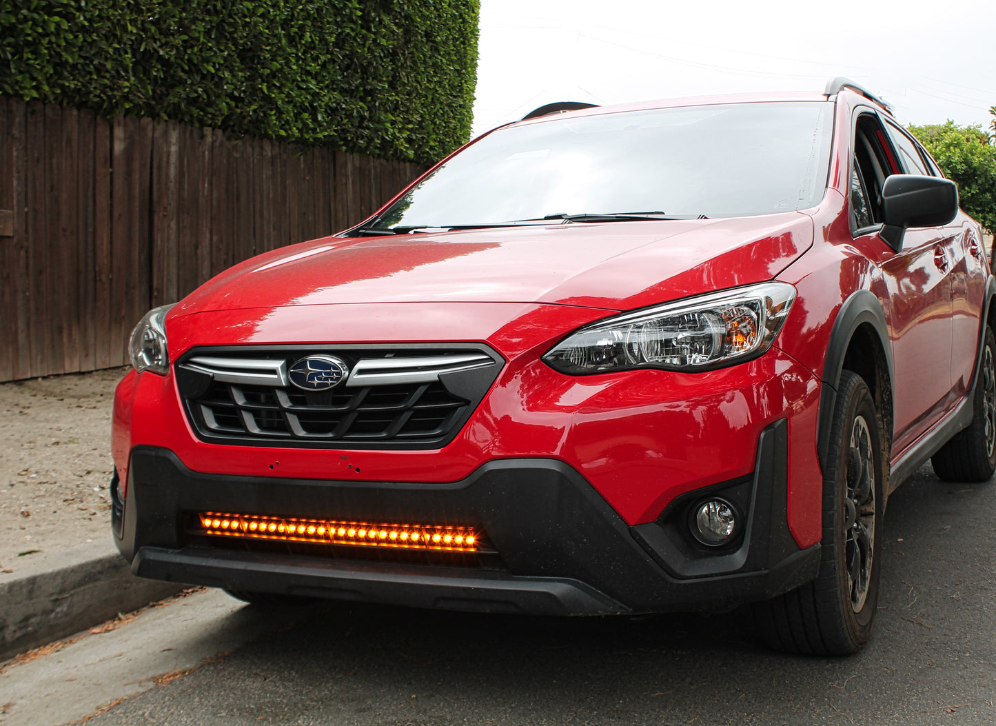 Red Subaru Crosstrek with additional LED lights on a driveway