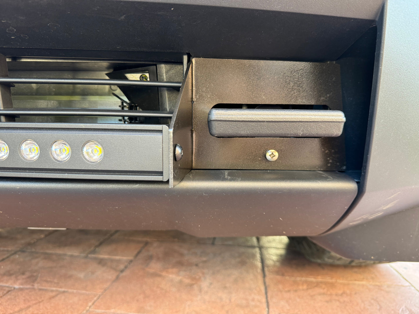 Close-up of a vehicle bumper with LED lights on a tiled floor.