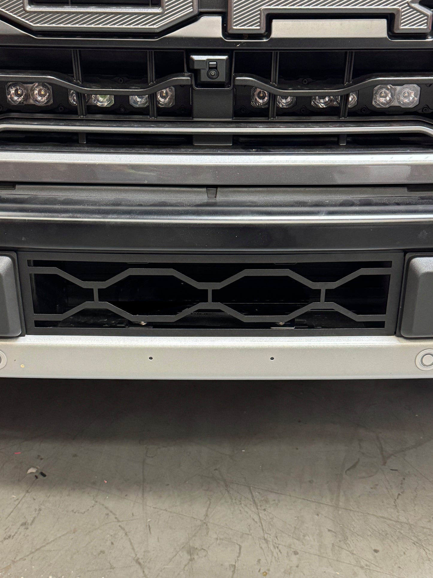 Close-up of a vehicle grille with a textured finish on a concrete surface