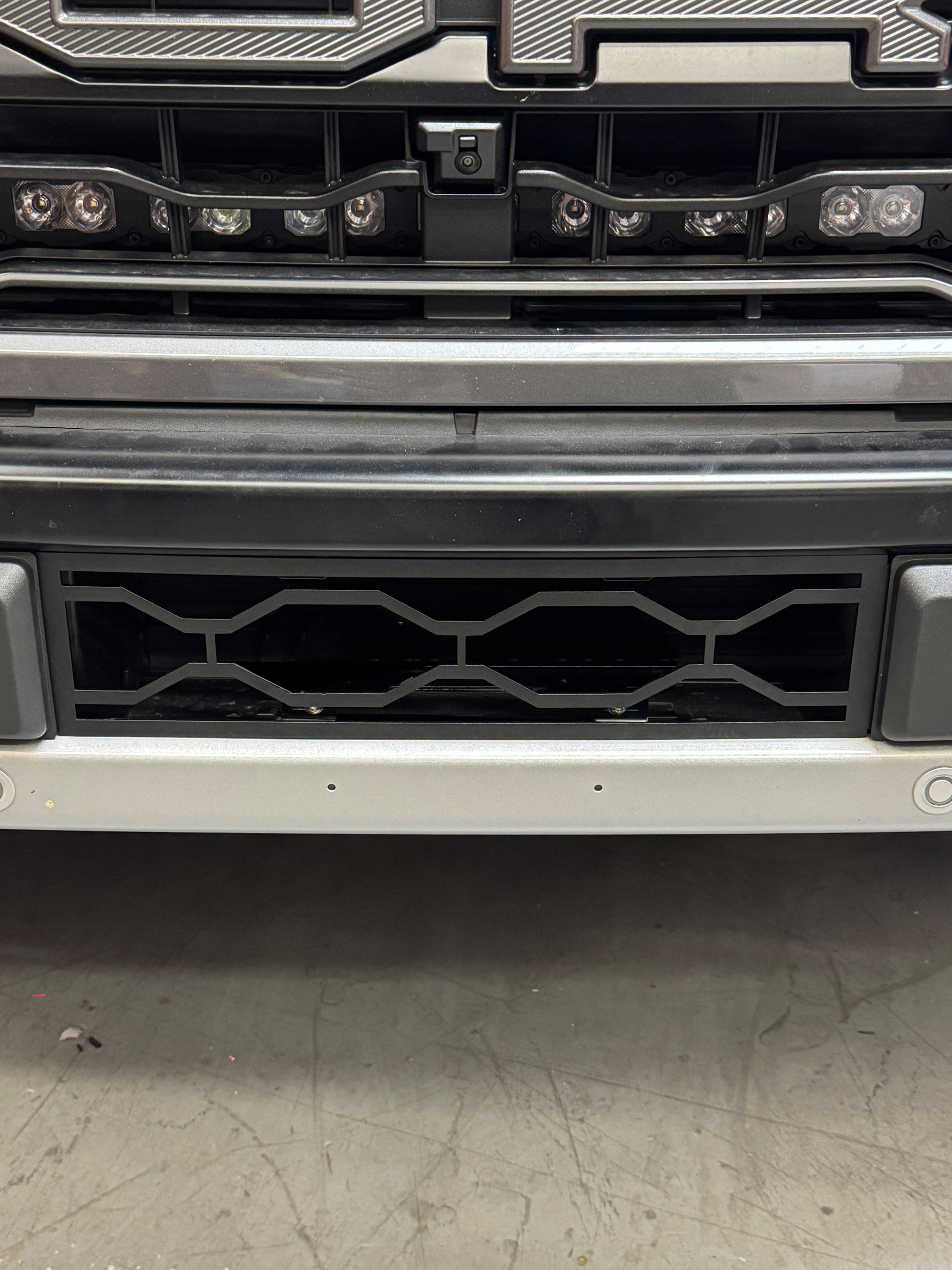 Close-up of a vehicle grille with a textured finish on a concrete surface