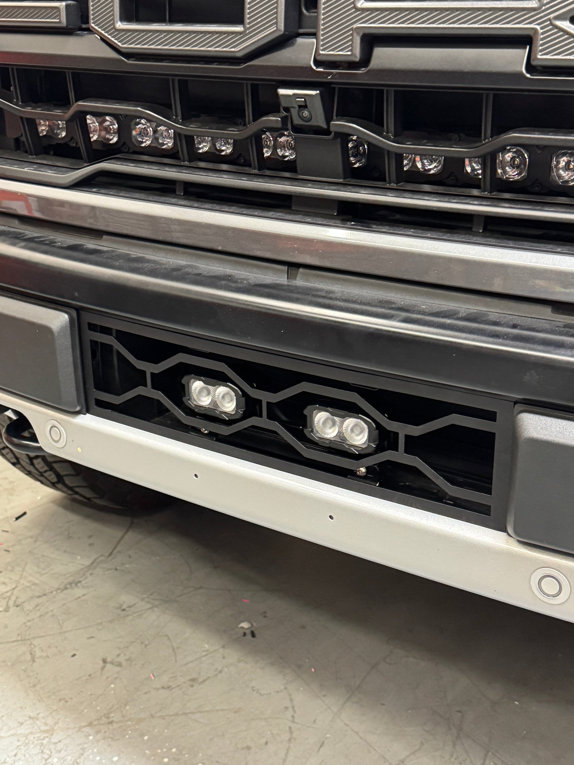 Close-up of a vehicle's front bumper with lights and grille / Ford Raptor Gen 3 Refresh Guard Plate