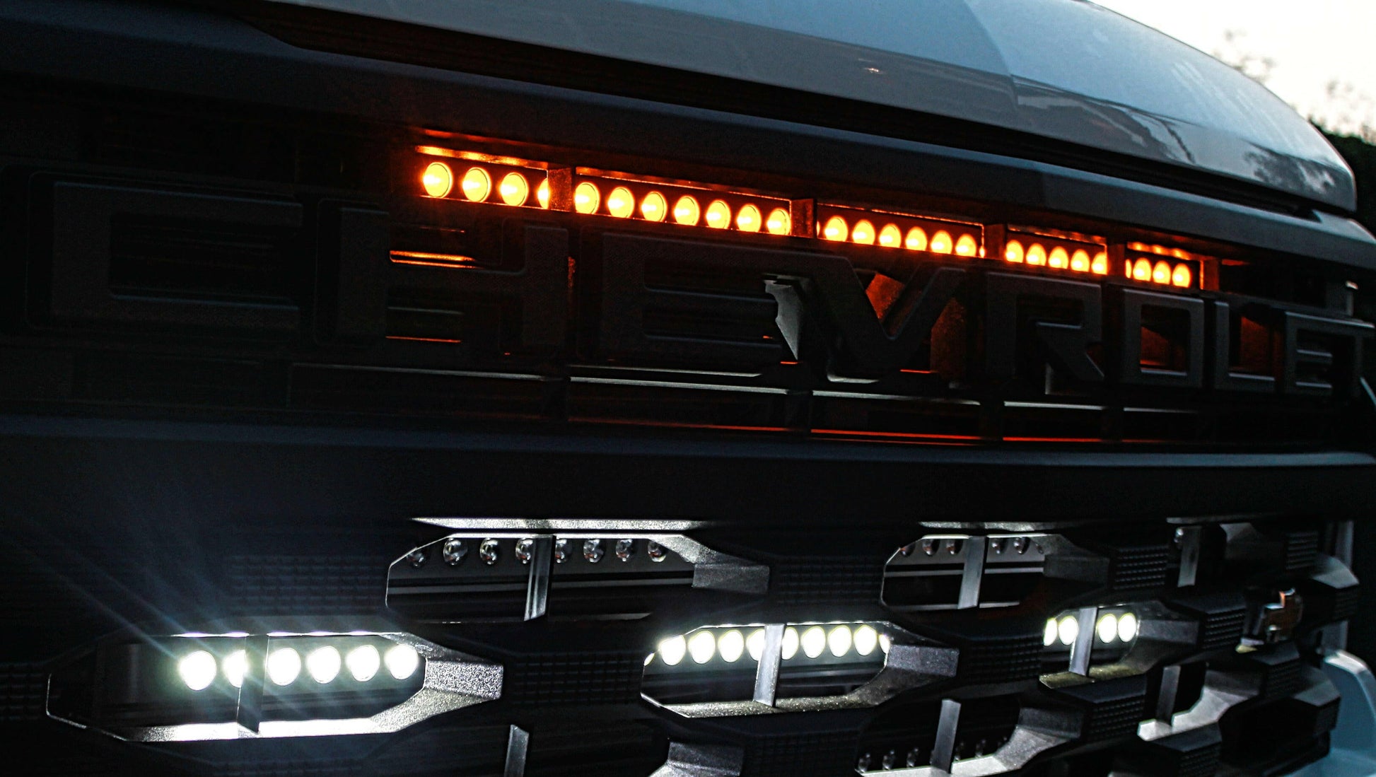 Close-up of a vehicle's front grille with LED lights on a dark background