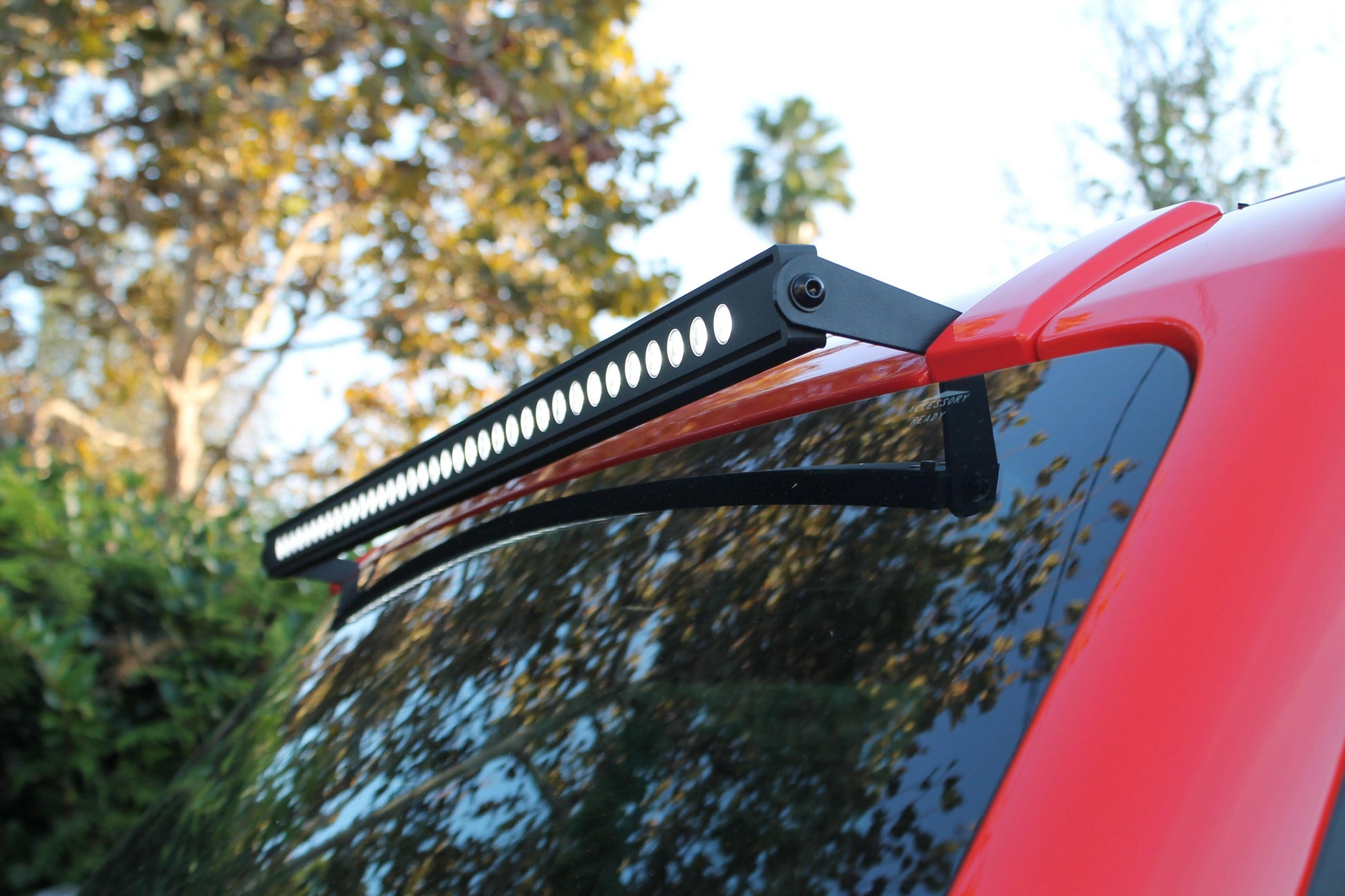 Car roof rack with LED light bar on a red car outdoors