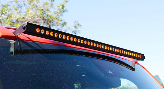 Car roof with an LED amber light bar attached, outdoors.
