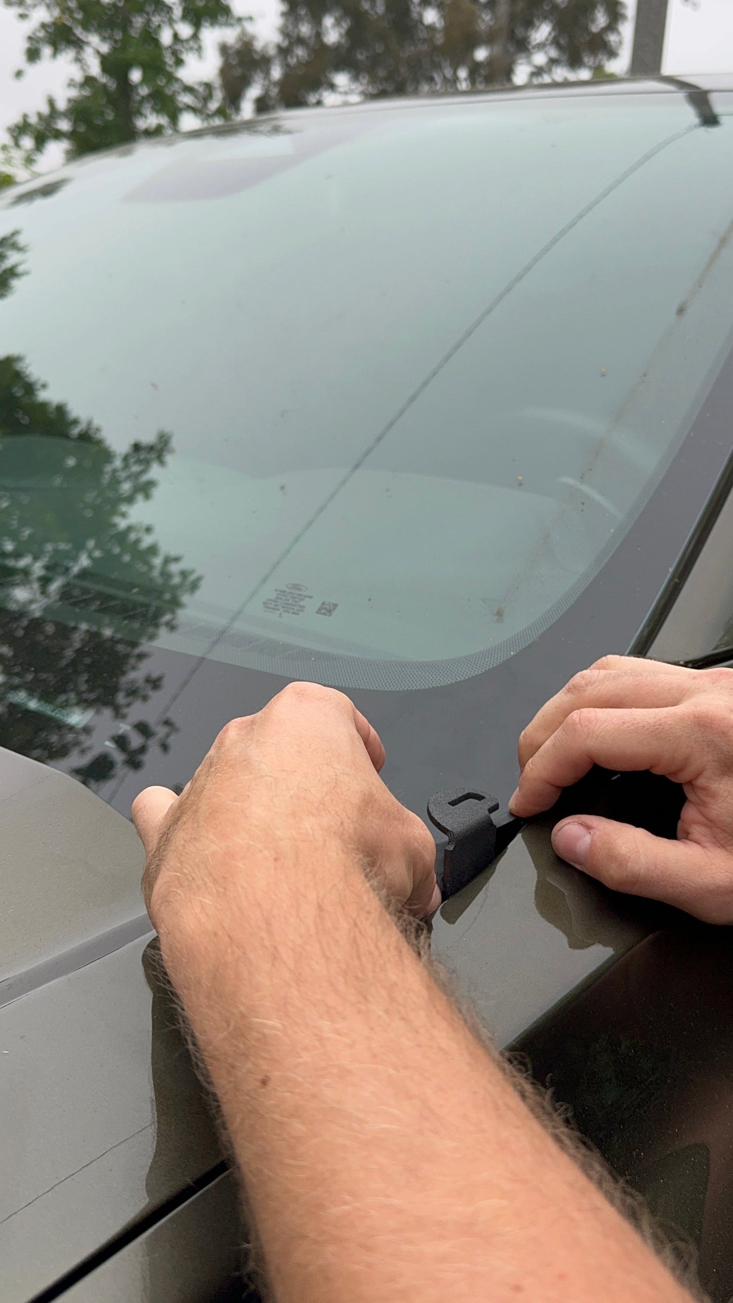 Person installing mounts for light bar on a vehicle outdoors.