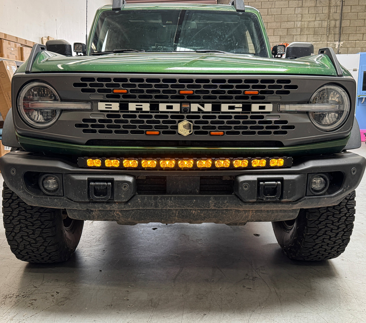 Front view of a green Ford Bronco truck with visible branding and amber LED Light Bar
