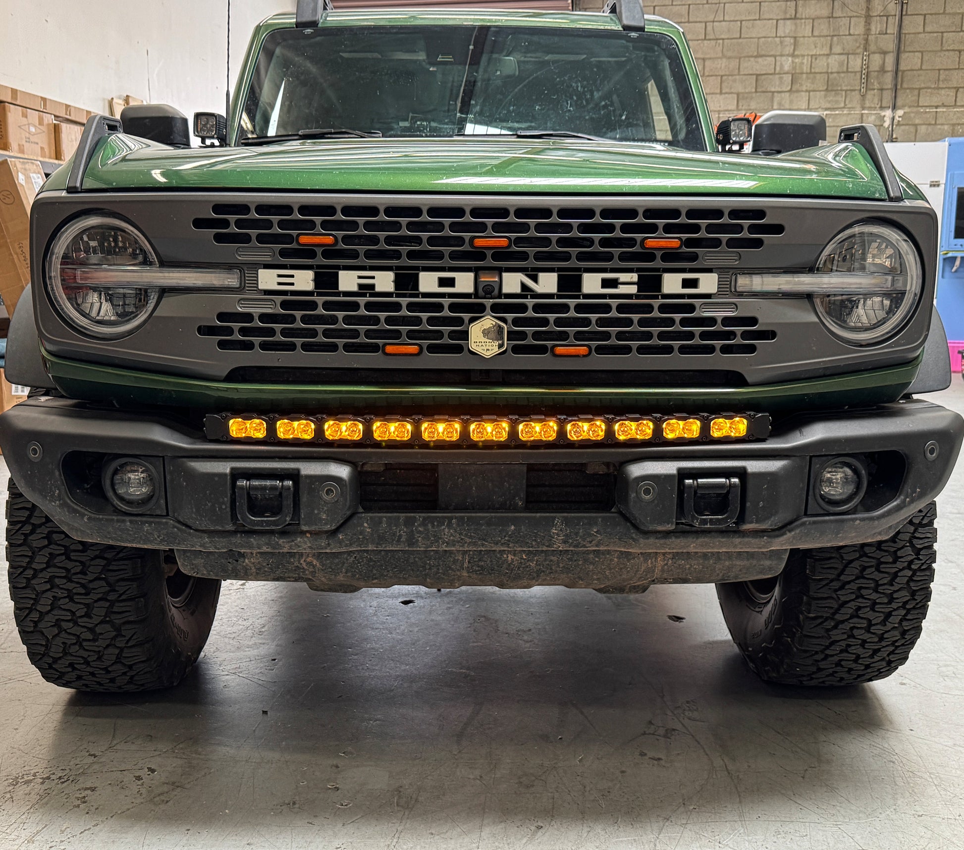 Front view of a green Ford Bronco truck with visible branding and amber LED Light Bar