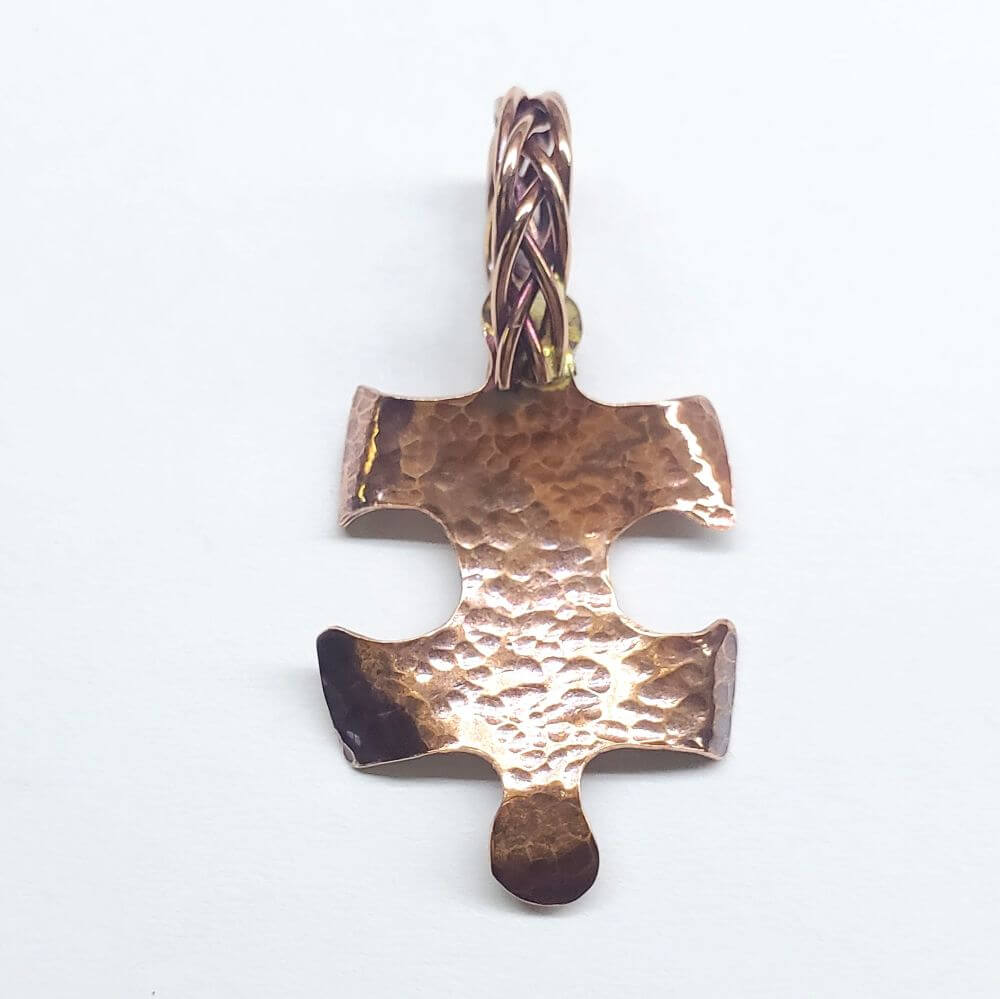 Bronze puzzle piece pendant on a white background
