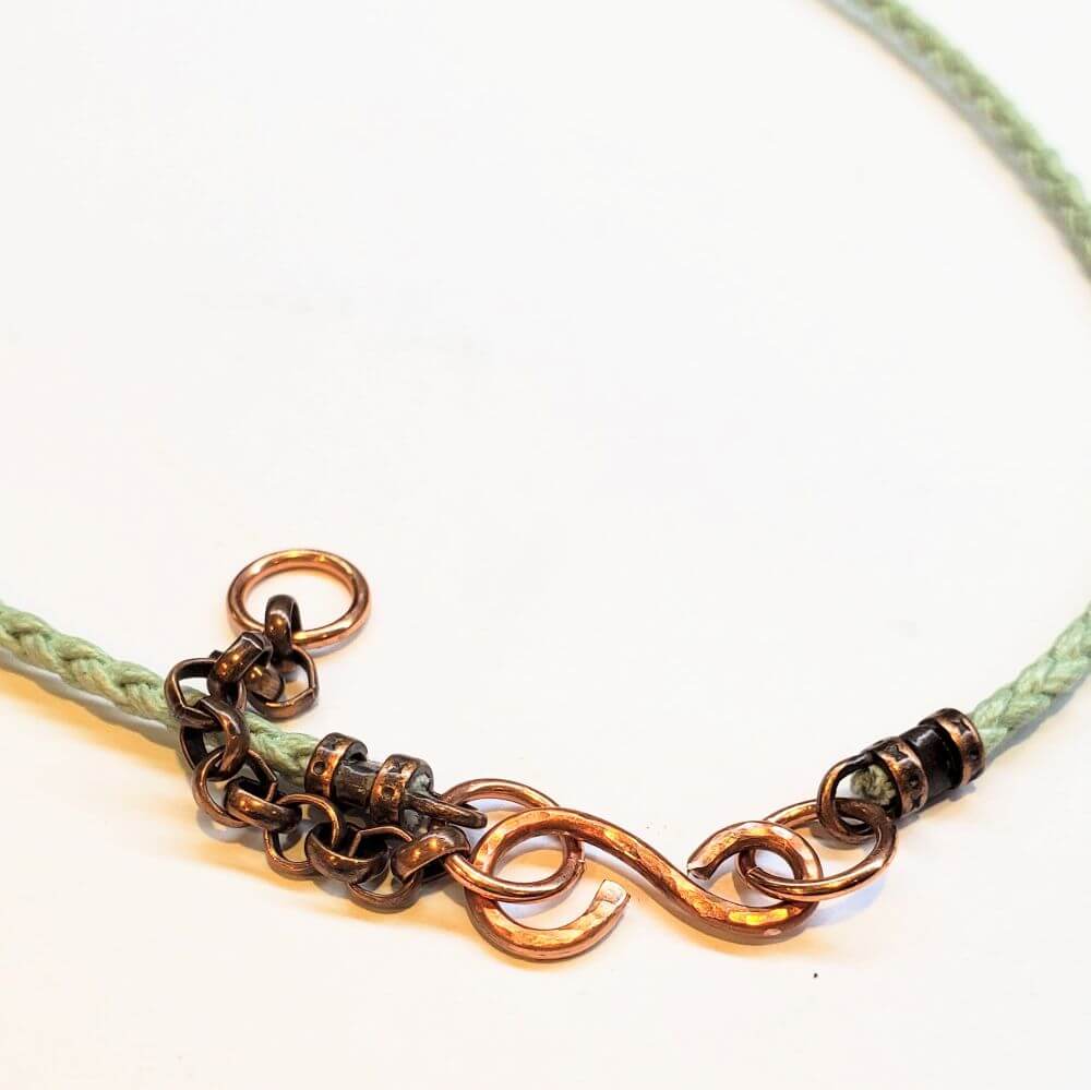 Necklace with chain and green cord on a white background