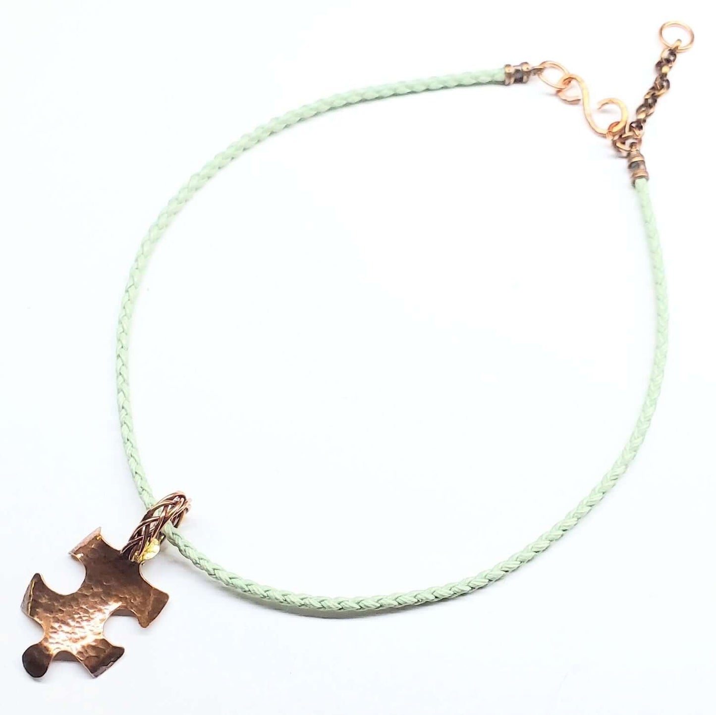 Autism Necklace with a green cord and a copper puzzle piece charm on a white background