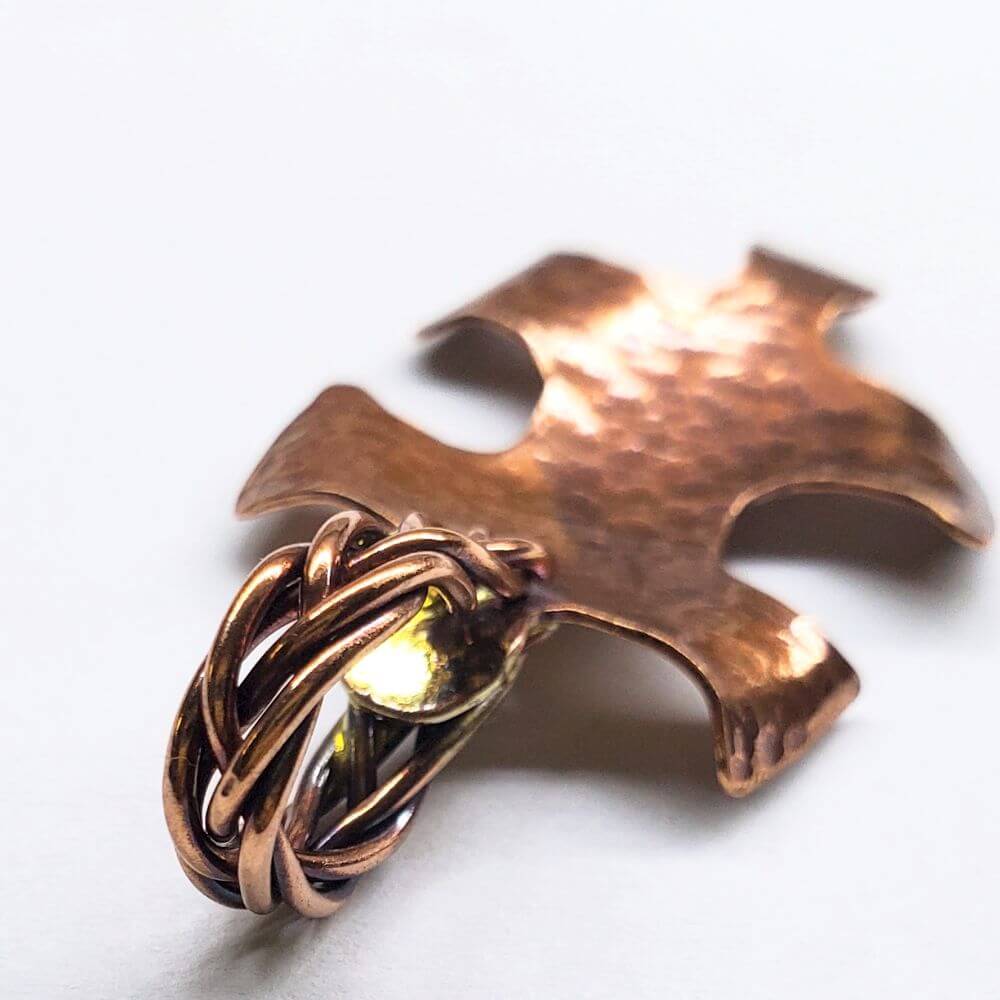 Copper puzzle piece pendant with interwoven design on a white background