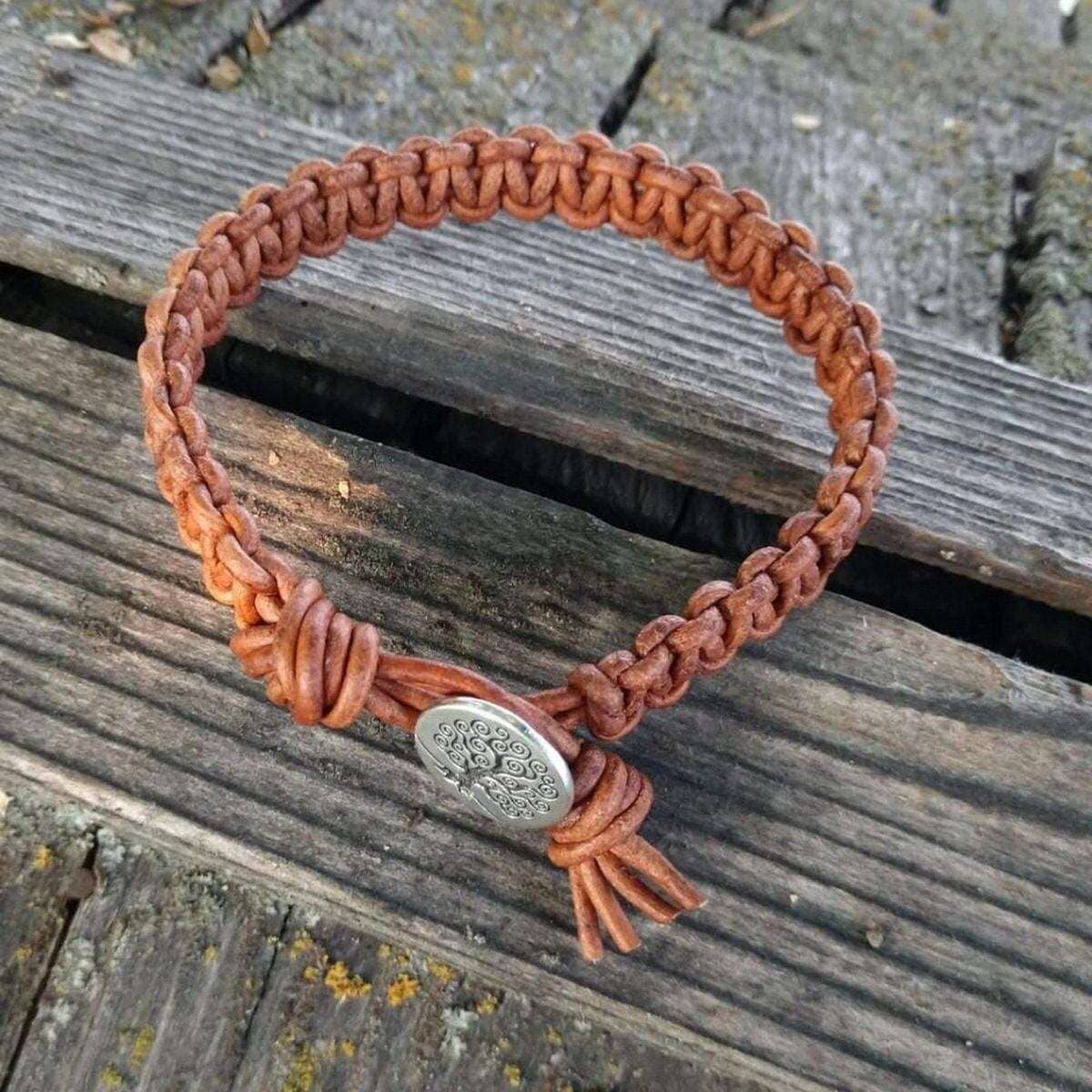 Brown braided bracelet with a silver button clasp on a wooden surface