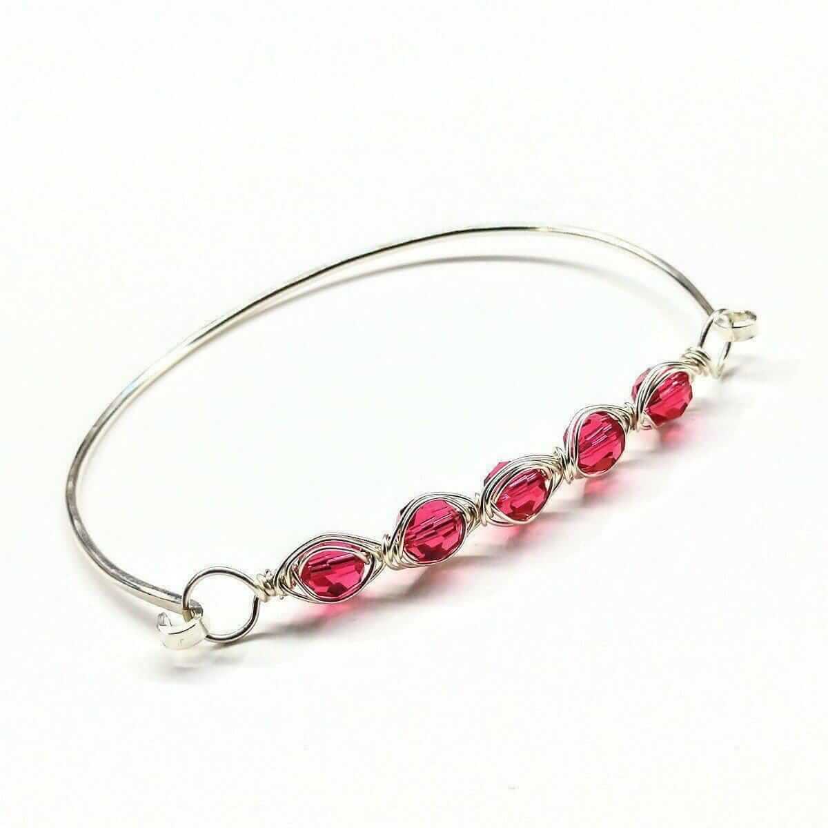 Silver bracelet with red gemstones on a white background