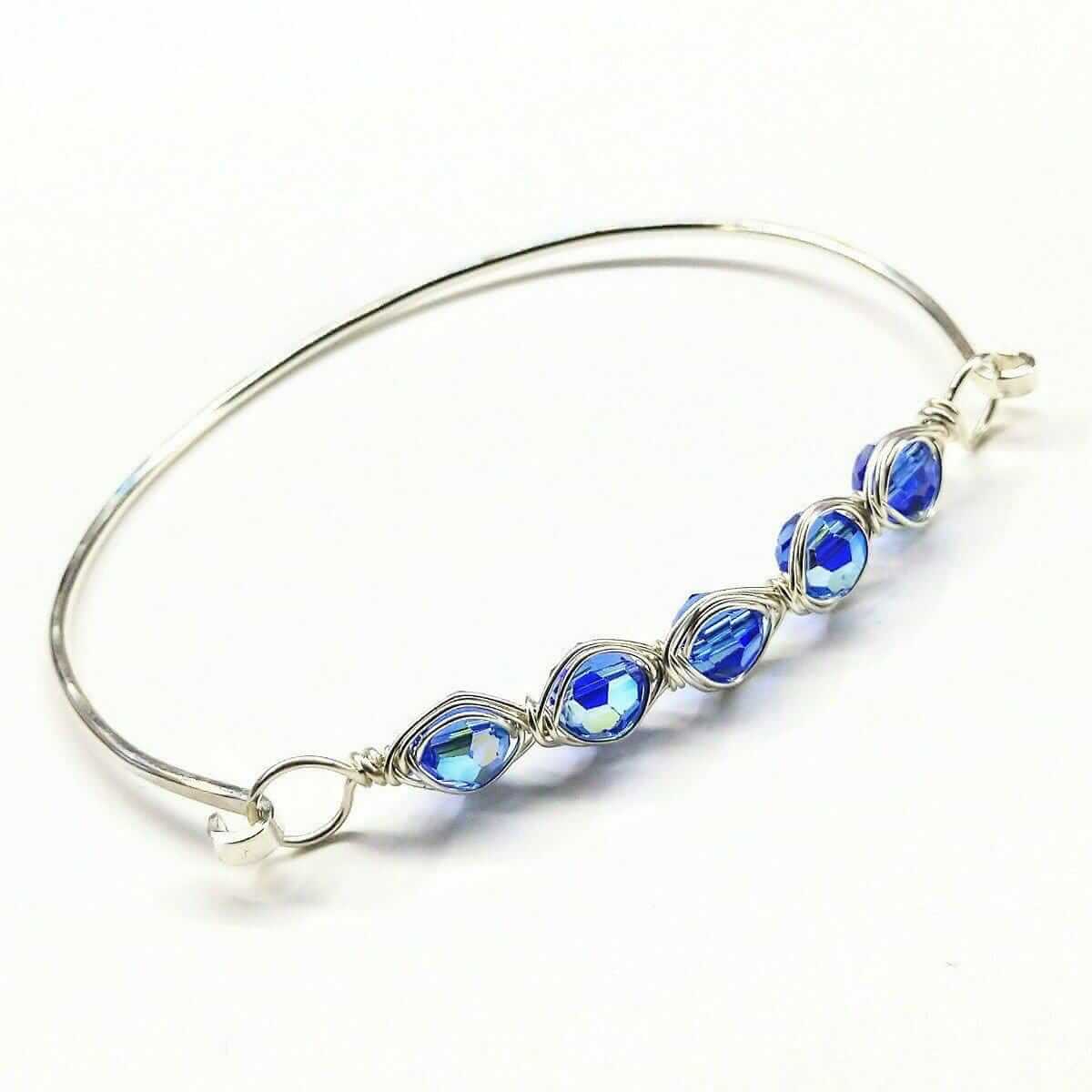 Silver bangle with blue gemstones on a white background