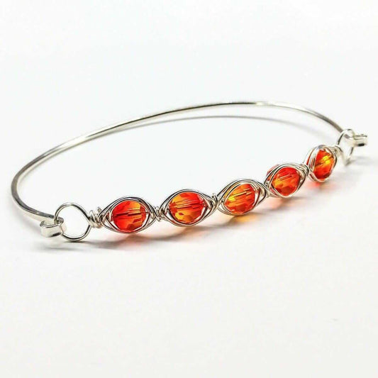 Silver bracelet with orange beads on a white background