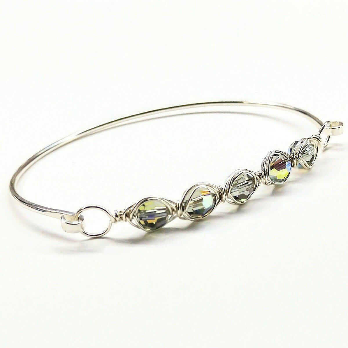 Silver bracelet with green beads on a white background
